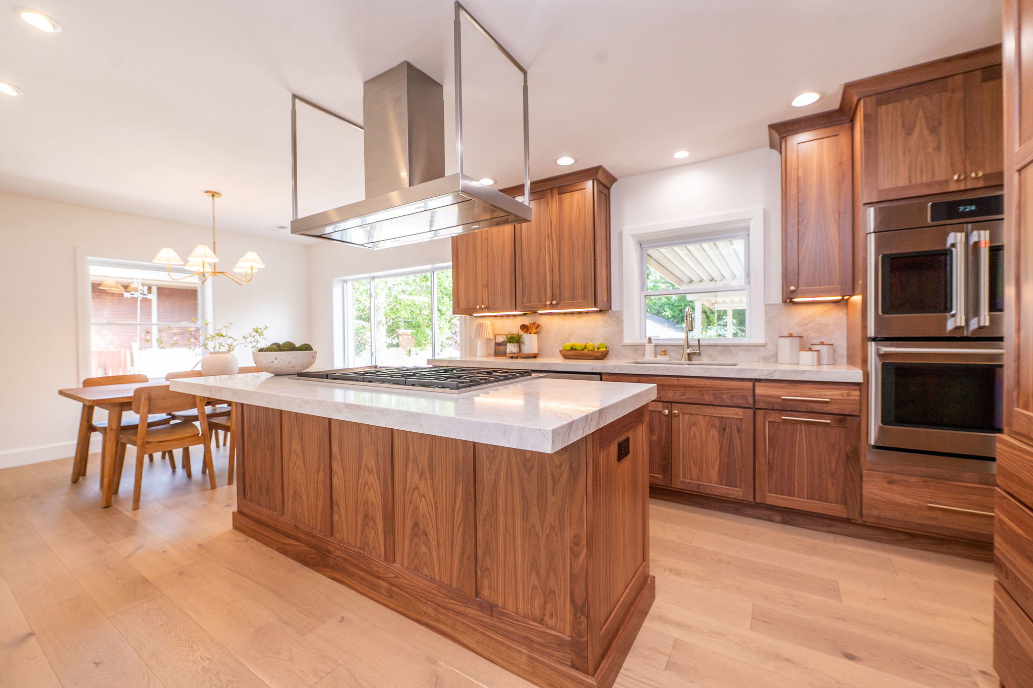 Gourmet kitchen with a large center island, rich wood-finish cabinetry, stainless steel appliances, and light wood-finish flooring