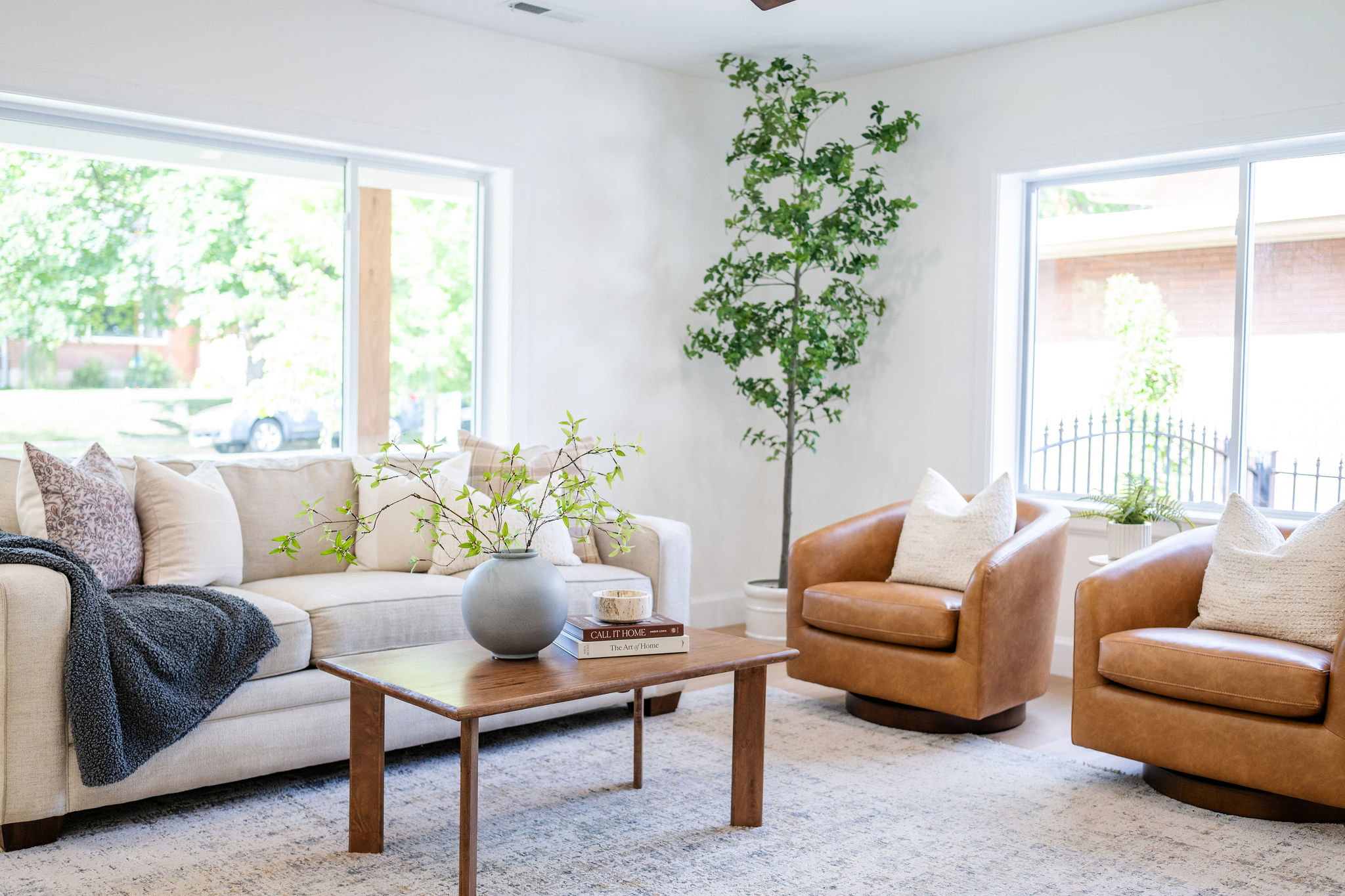 Spacious living area featuring expansive windows, light-toned walls, and wood-finish flooring