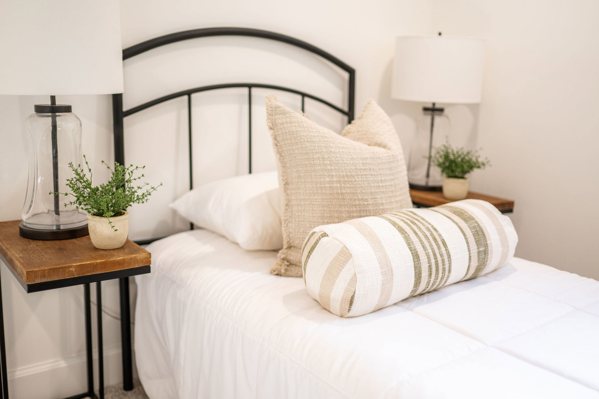 Bedroom featuring a black metal bed frame with matching wood-finish top side tables