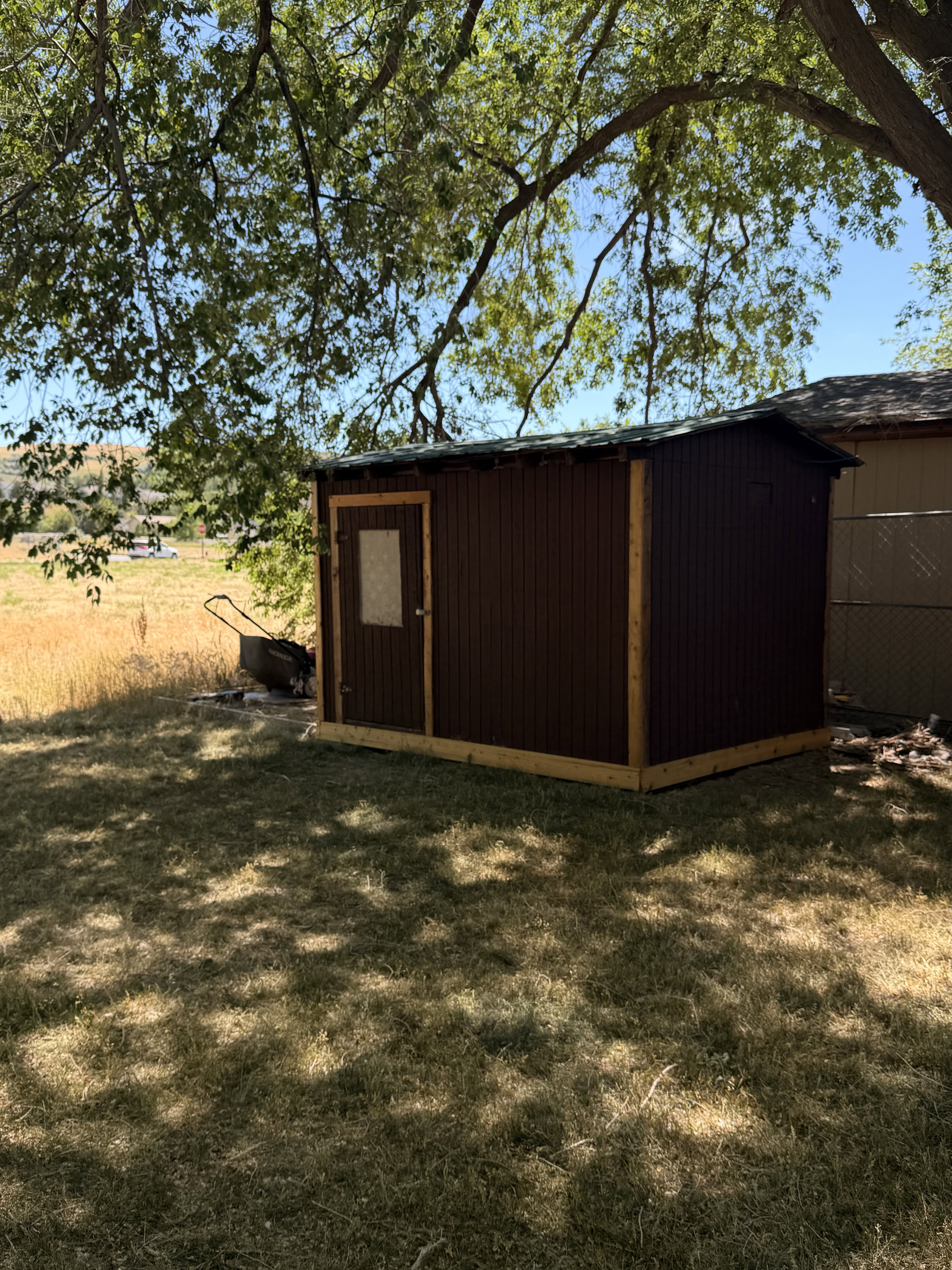 Utility shed featuring brown corrugated metal siding, wood trim, and a metal roof