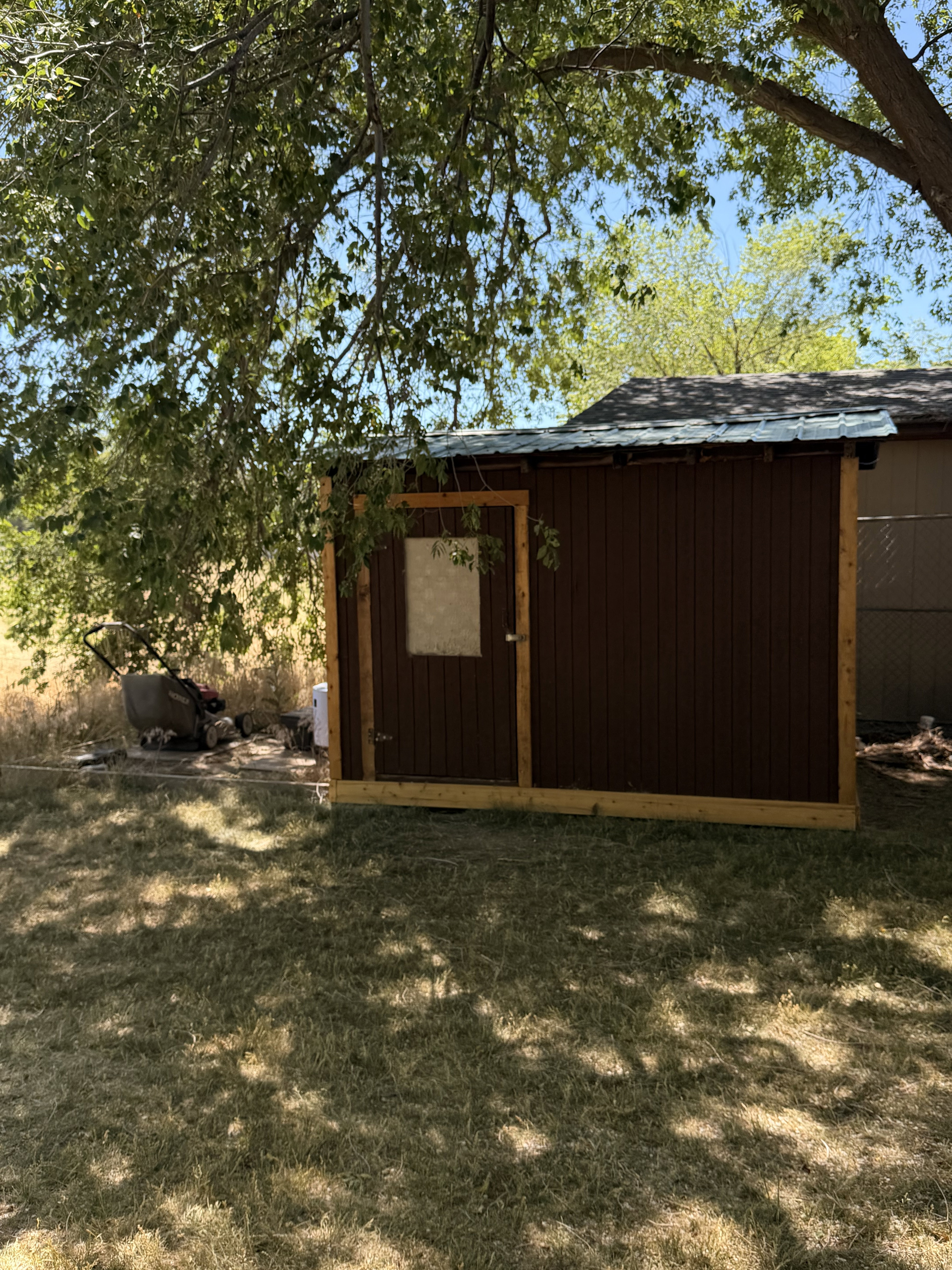 Wood-paneled shed with a metal roof and a single entry door