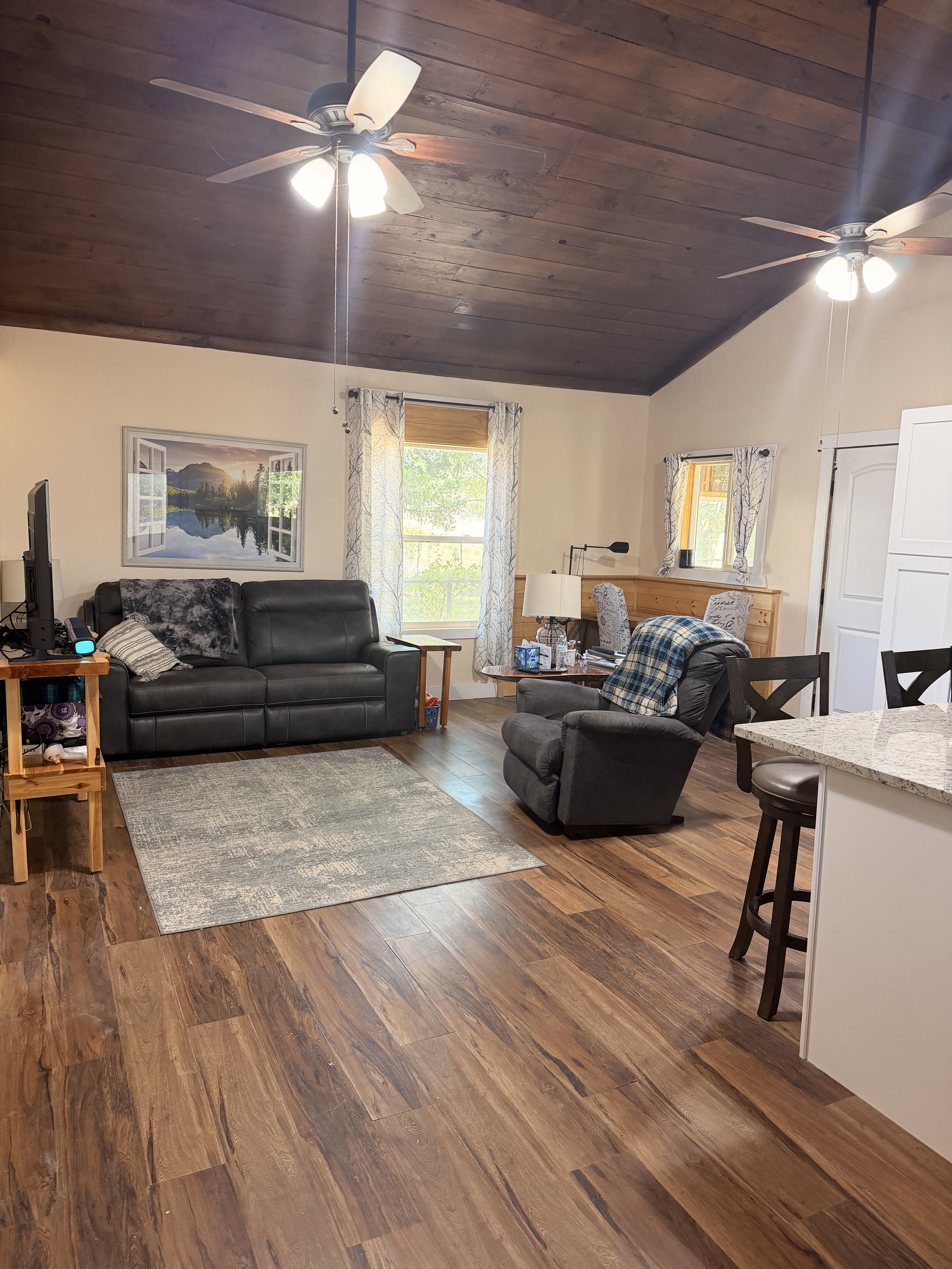 Vaulted wood-paneled ceiling with two ceiling fans, wood-finish flooring, and light-toned wall paint