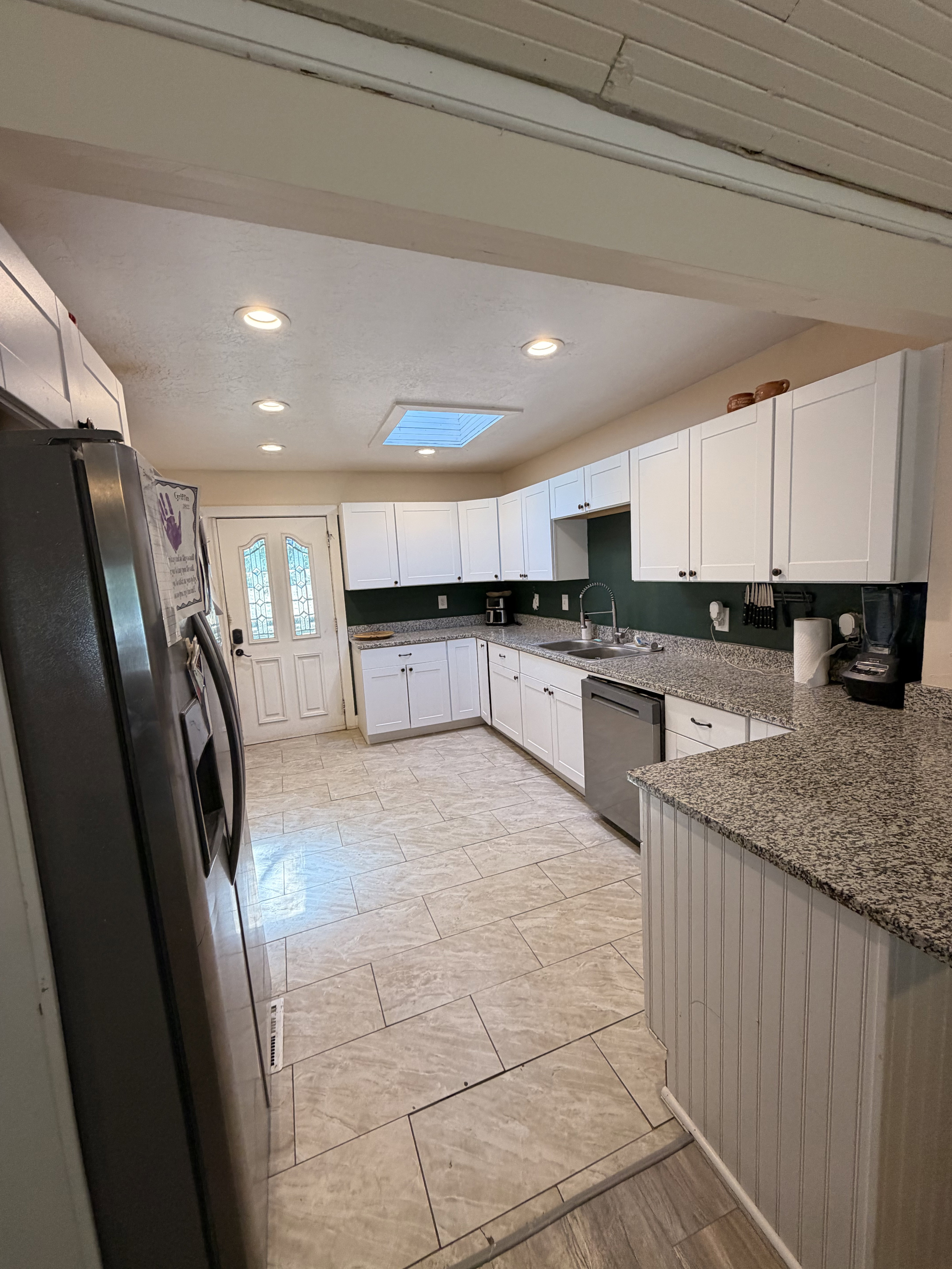 Kitchen featuring white cabinetry, speckled countertops, stainless steel appliances, recessed lighting, and a skylight