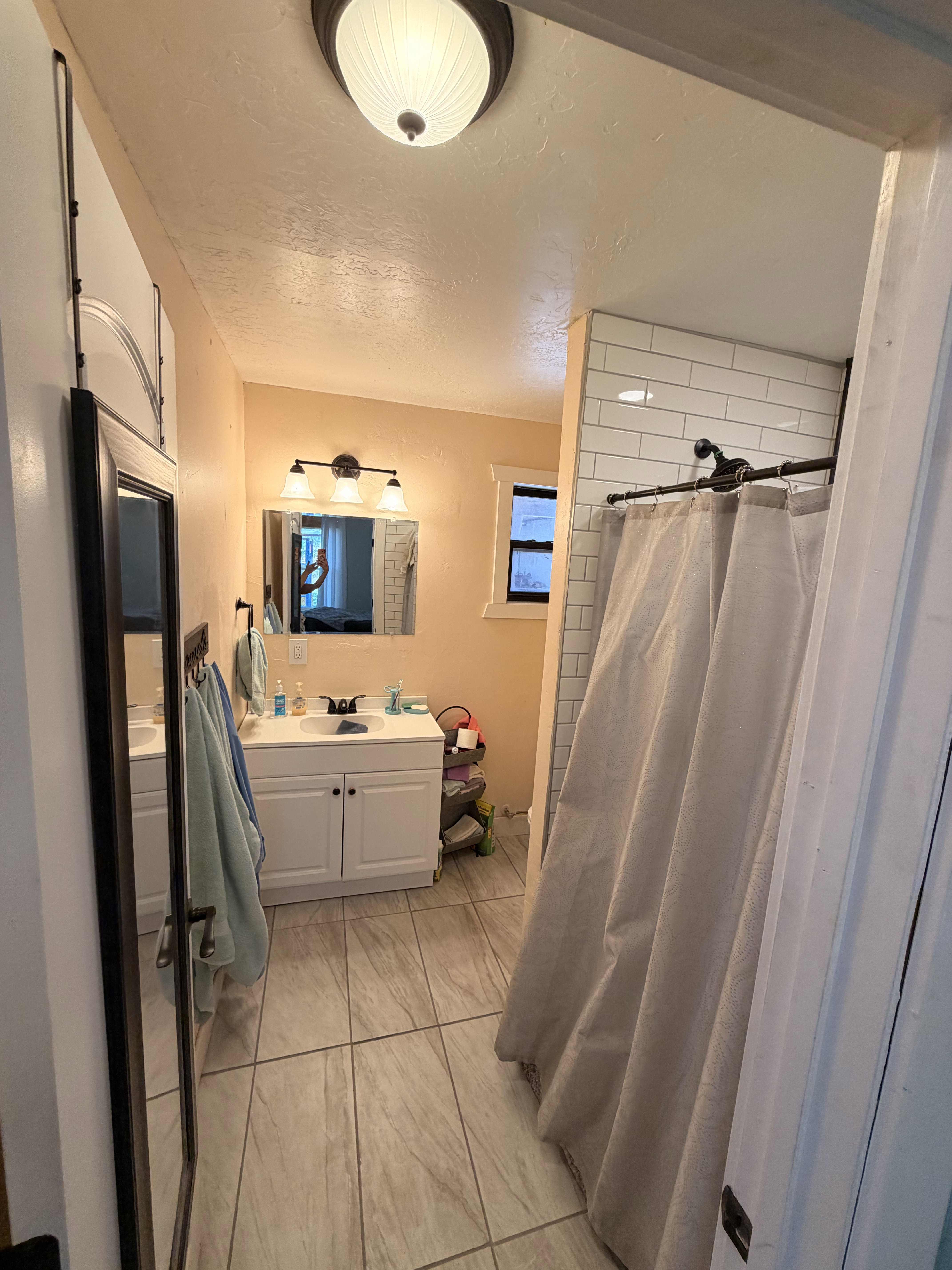 Bathroom featuring a single vanity with white cabinetry, a rectangular mirror, and a wall-mounted light fixture