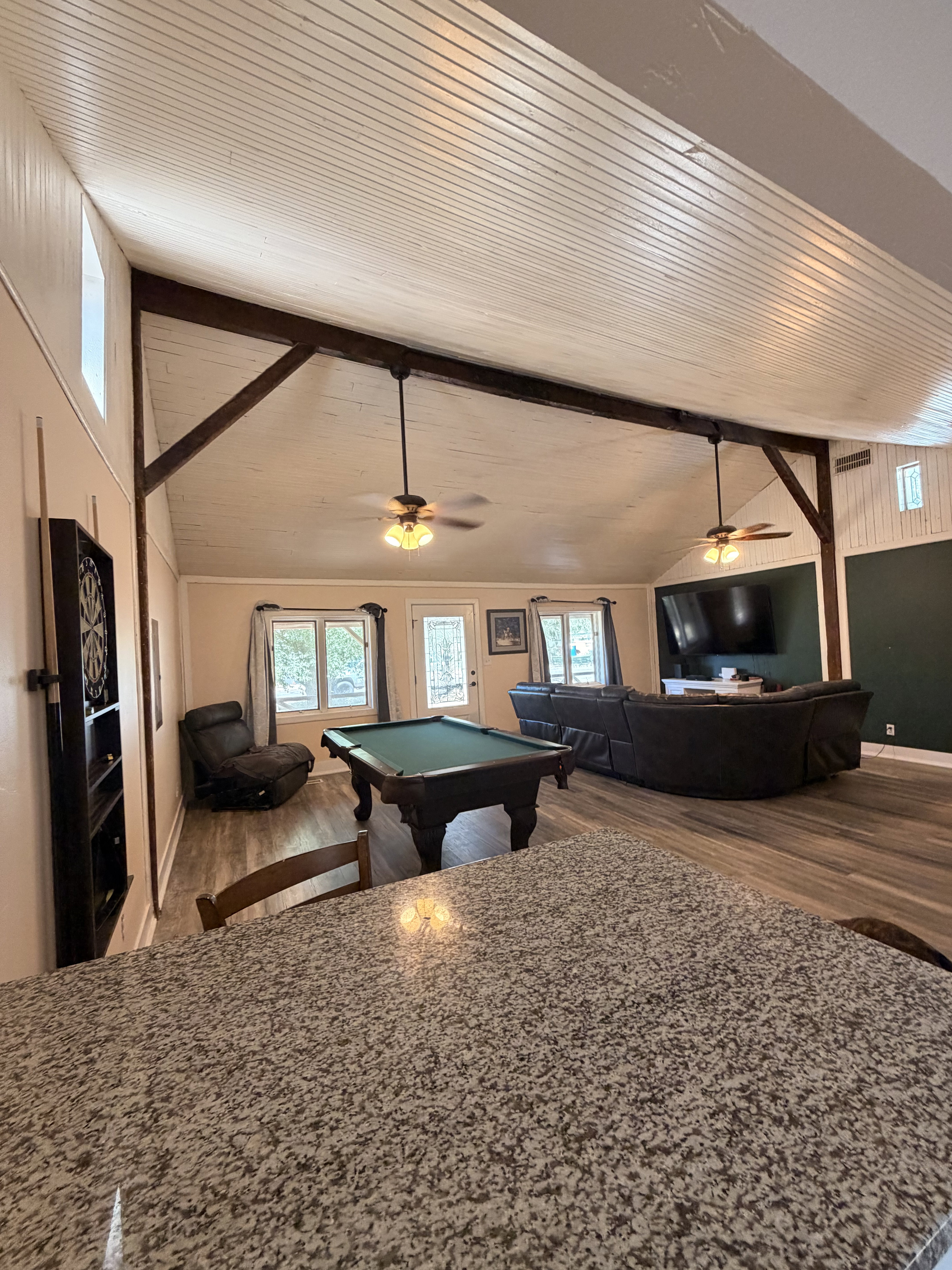 Spacious open-concept room featuring a vaulted tongue-and-groove ceiling with exposed wood beams