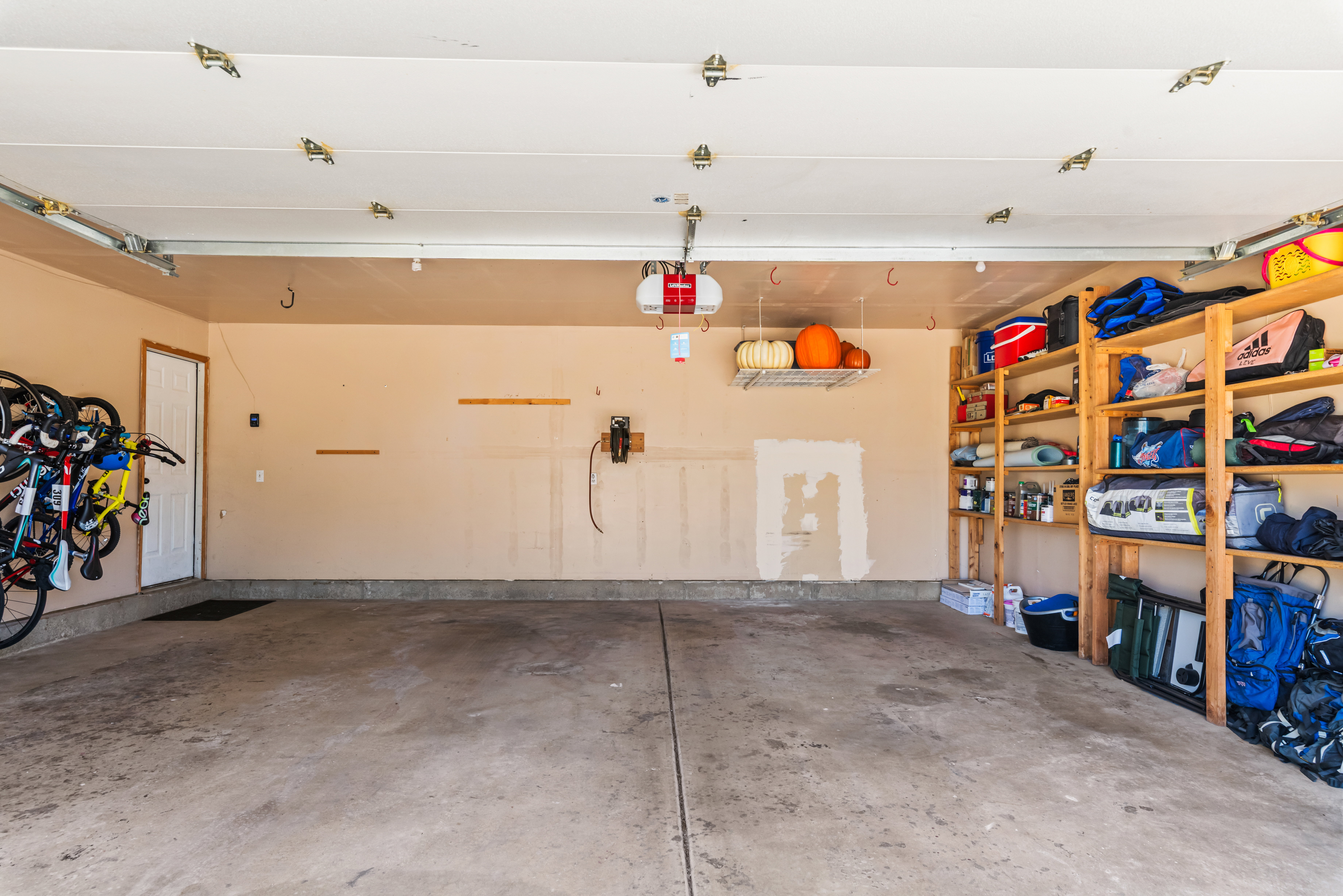 Spacious two-car garage featuring a durable concrete floor, an overhead garage door, and a side access door