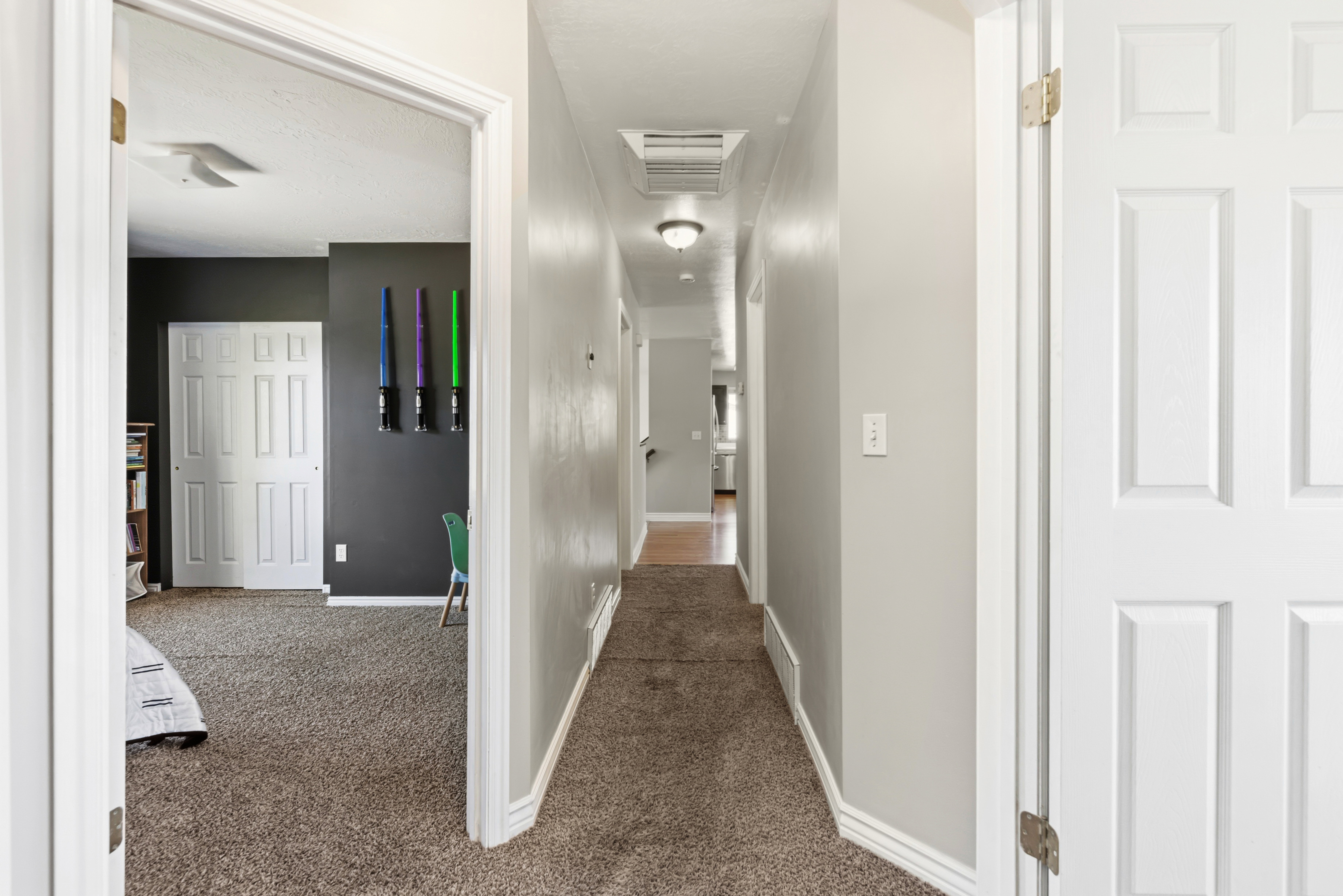 Hallway featuring light gray walls, brown carpet flooring, and white baseboards