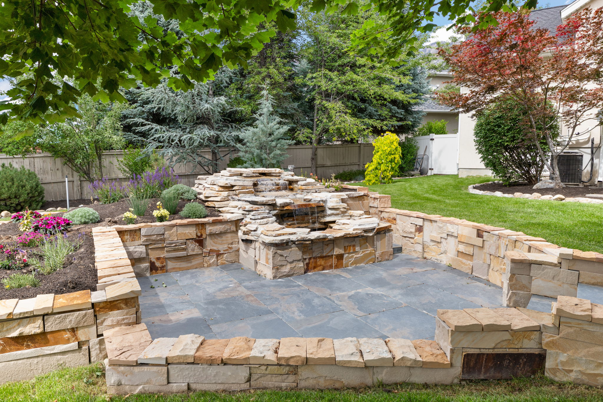 Stone patio featuring a built-in multi-tier water feature and integrated stone planters