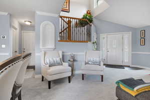 Two-story foyer with a decorative arched wall niche, hardwood and wrought iron staircase, and a front entry door with decorative glass sidelights