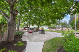 Expansive backyard featuring a natural stone patio, mature trees, and a manicured lawn