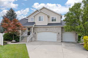Traditional-style house with brick siding, concrete driveway, an attached garage, solar panels, and stucco siding