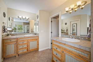 Bathroom featuring two vanities, a shower stall, and light tile patterned floors