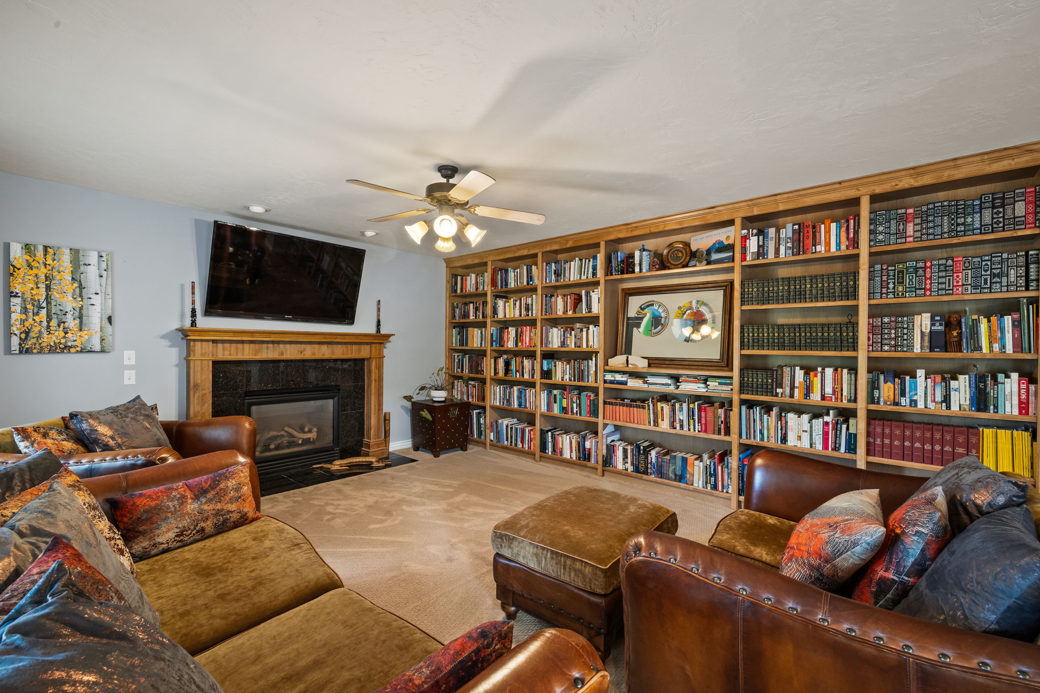 Living area with a fireplace, carpet floors, and ceiling fan