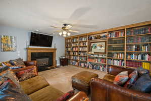 Living area with a fireplace, carpet floors, and ceiling fan