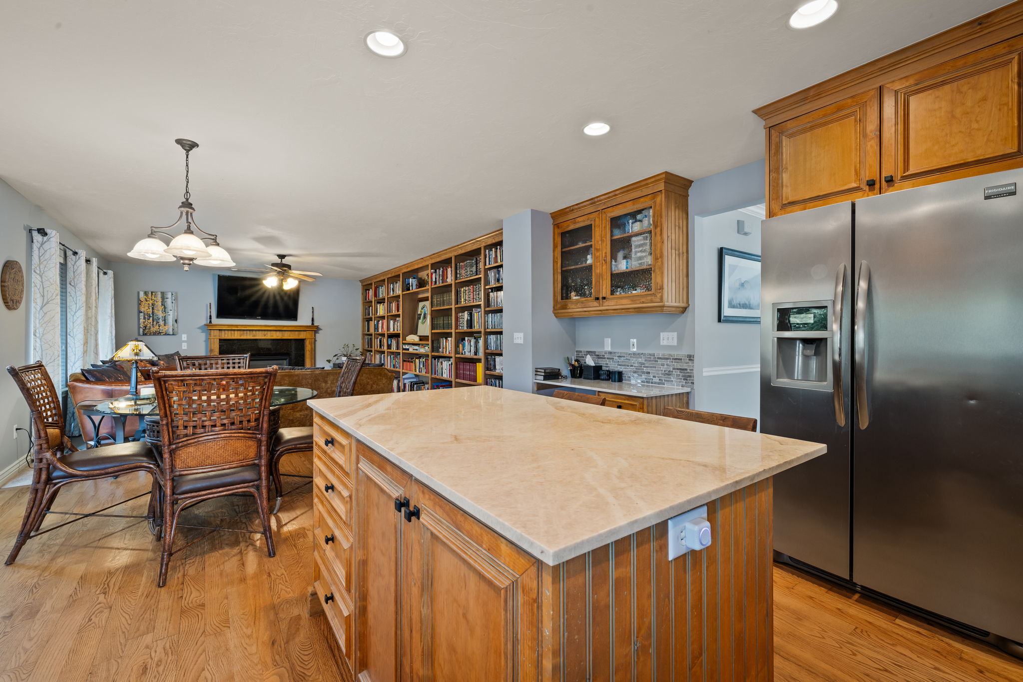 Kitchen with brown cabinetry, stainless steel fridge with ice dispenser, a fireplace, a center island, and light wood-type flooring
