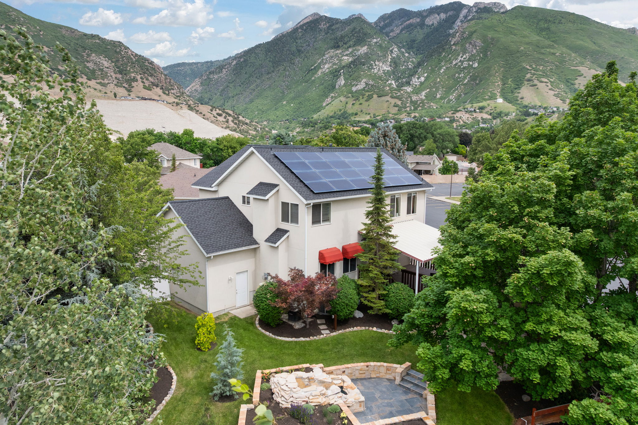 Stucco exterior with contrasting dark shingle roofing and integrated solar panels