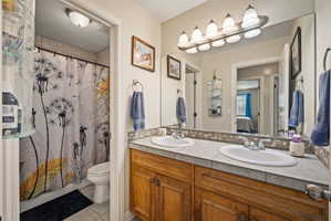 Bathroom with ensuite bathroom, light tile patterned flooring, double vanity, and shower / bath combo