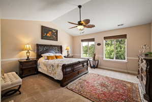 Bedroom featuring lofted ceiling, a ceiling fan, and light carpet