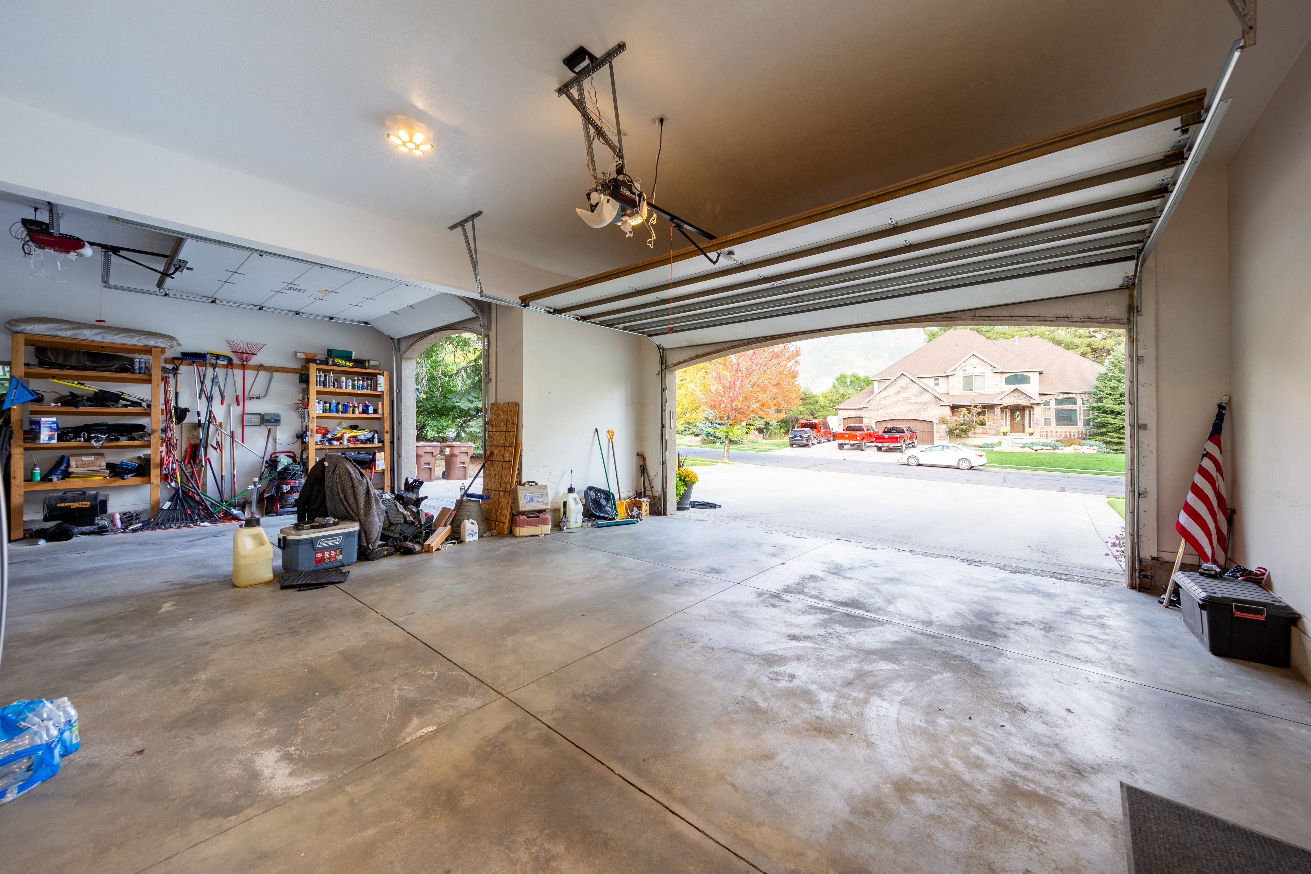 Spacious three-car garage featuring a concrete floor, overhead lighting, and two garage door openers