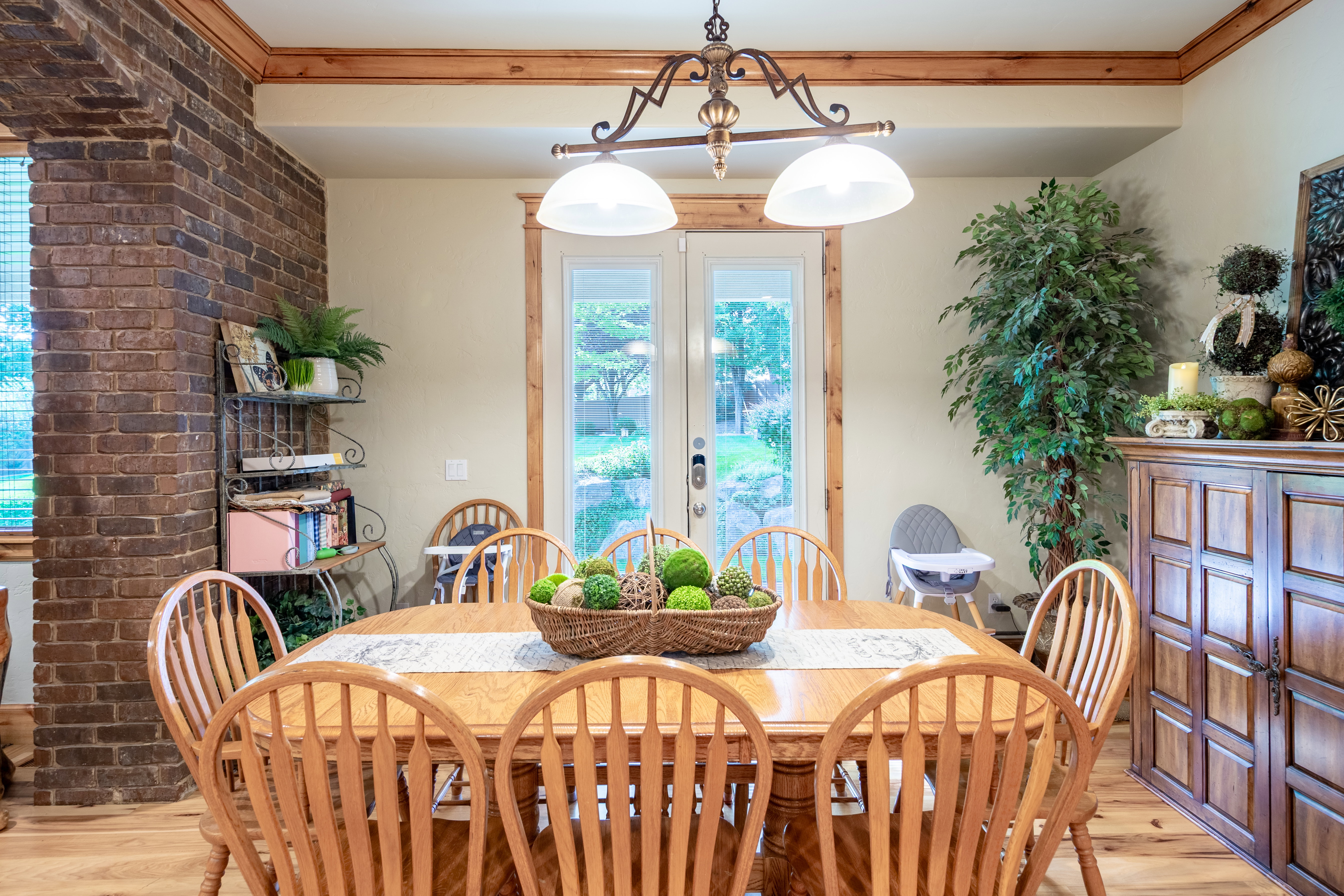 Dining area featuring wood-finish flooring, a decorative brick column, and French doors providing exterior access