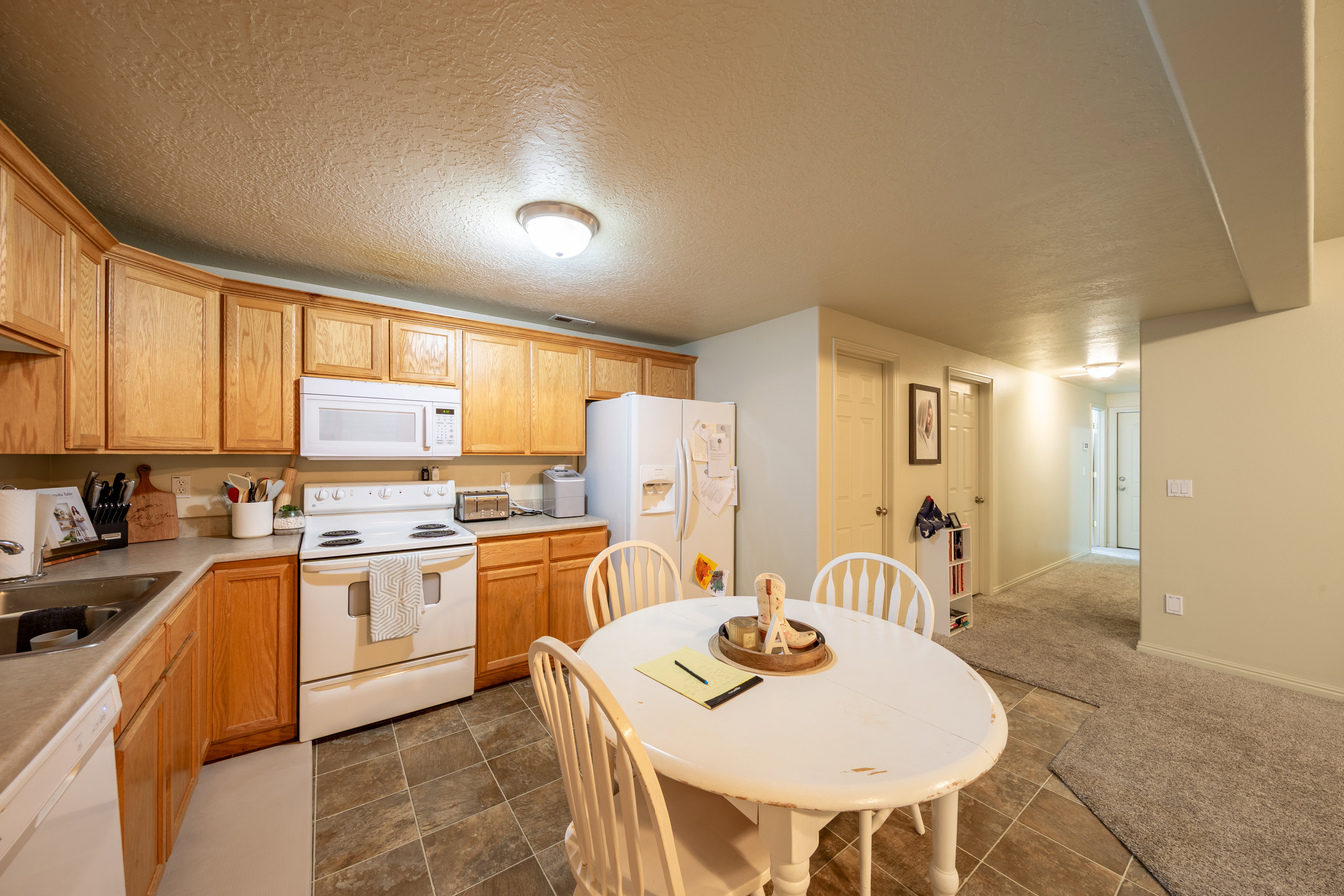Kitchen featuring wood-finish cabinetry, white appliances, and tiled flooring