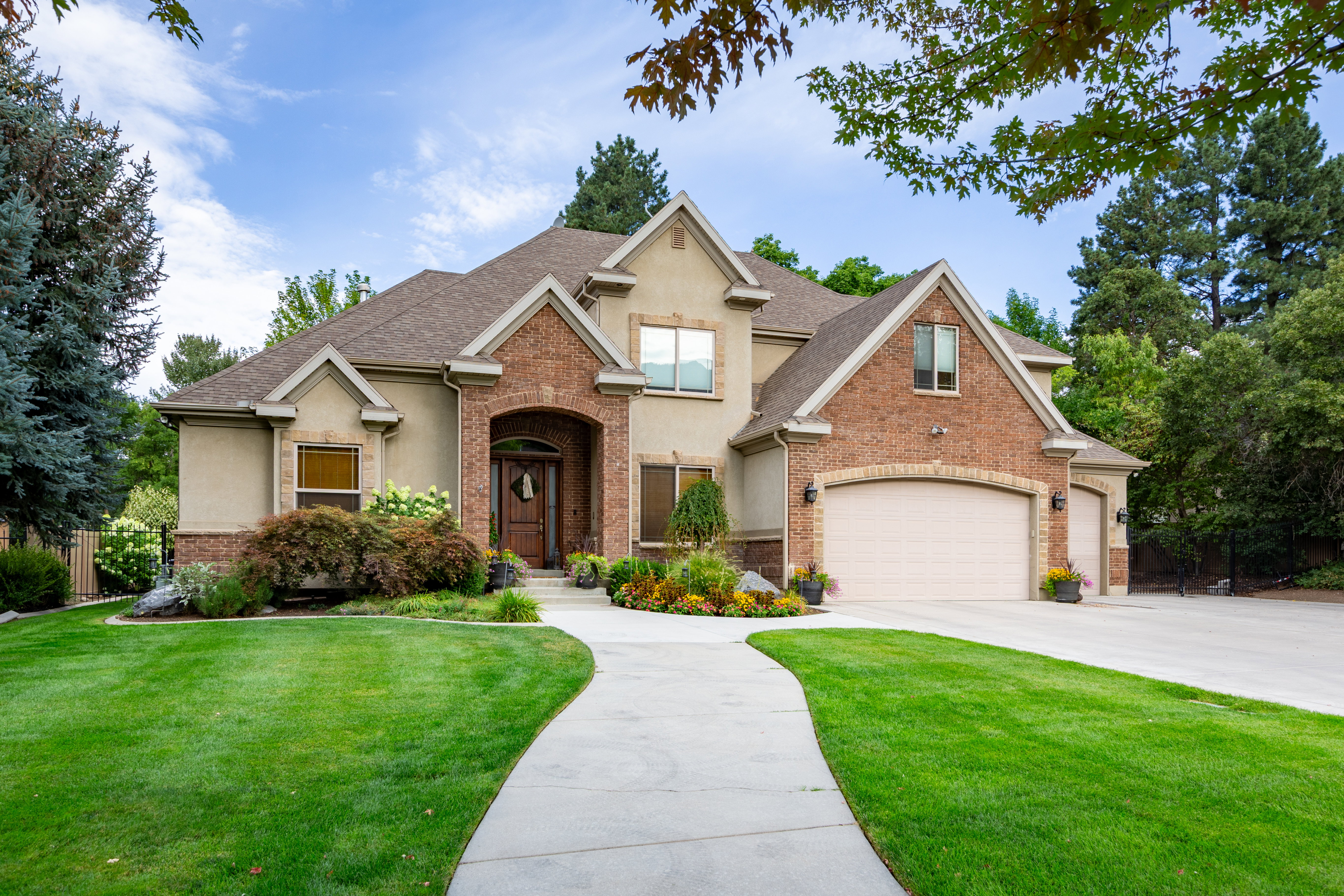 Stucco and brick facade residence featuring a prominent arched entry, multiple gables, and a concrete driveway
