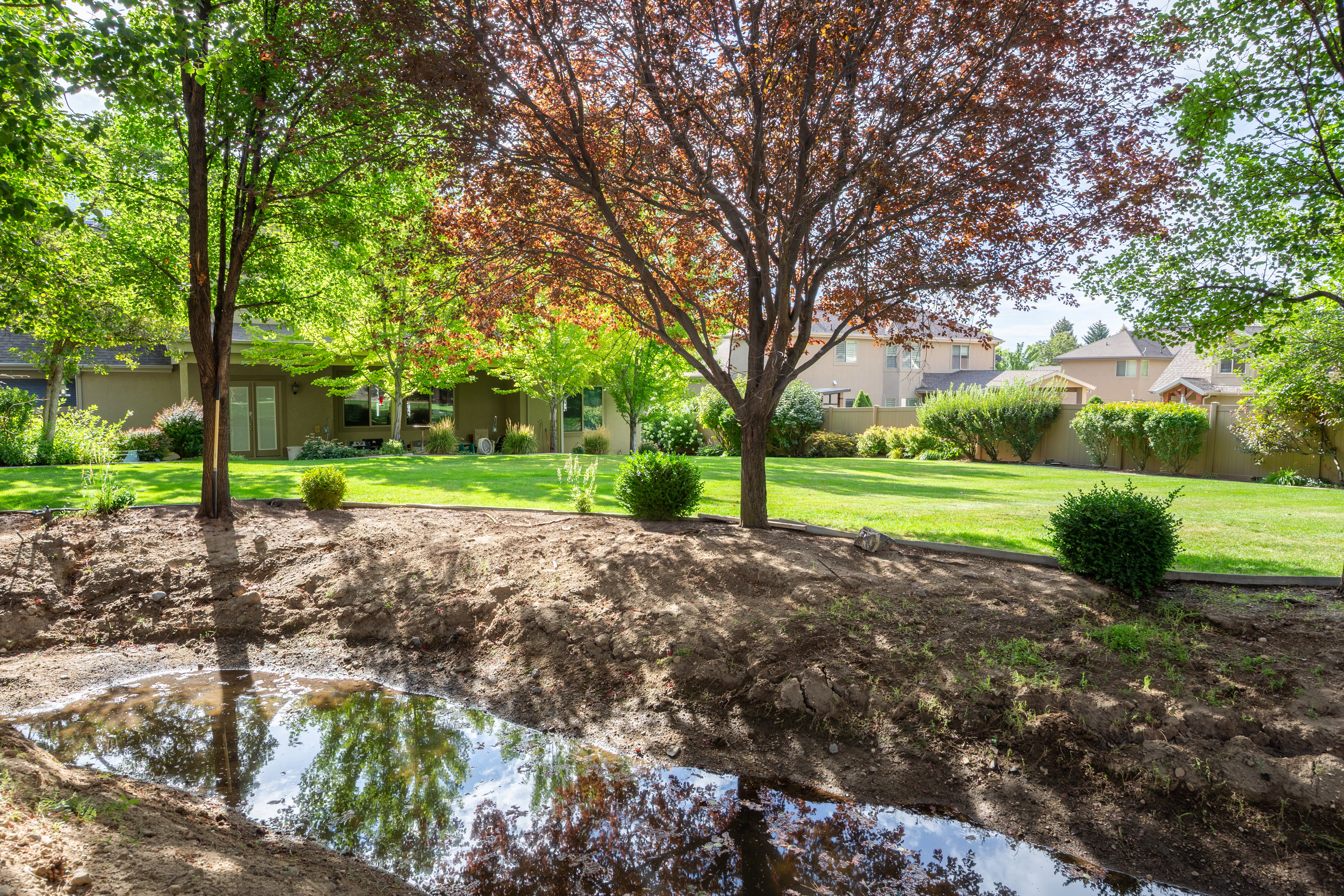 Expansive green lawn with mature trees and established landscaping