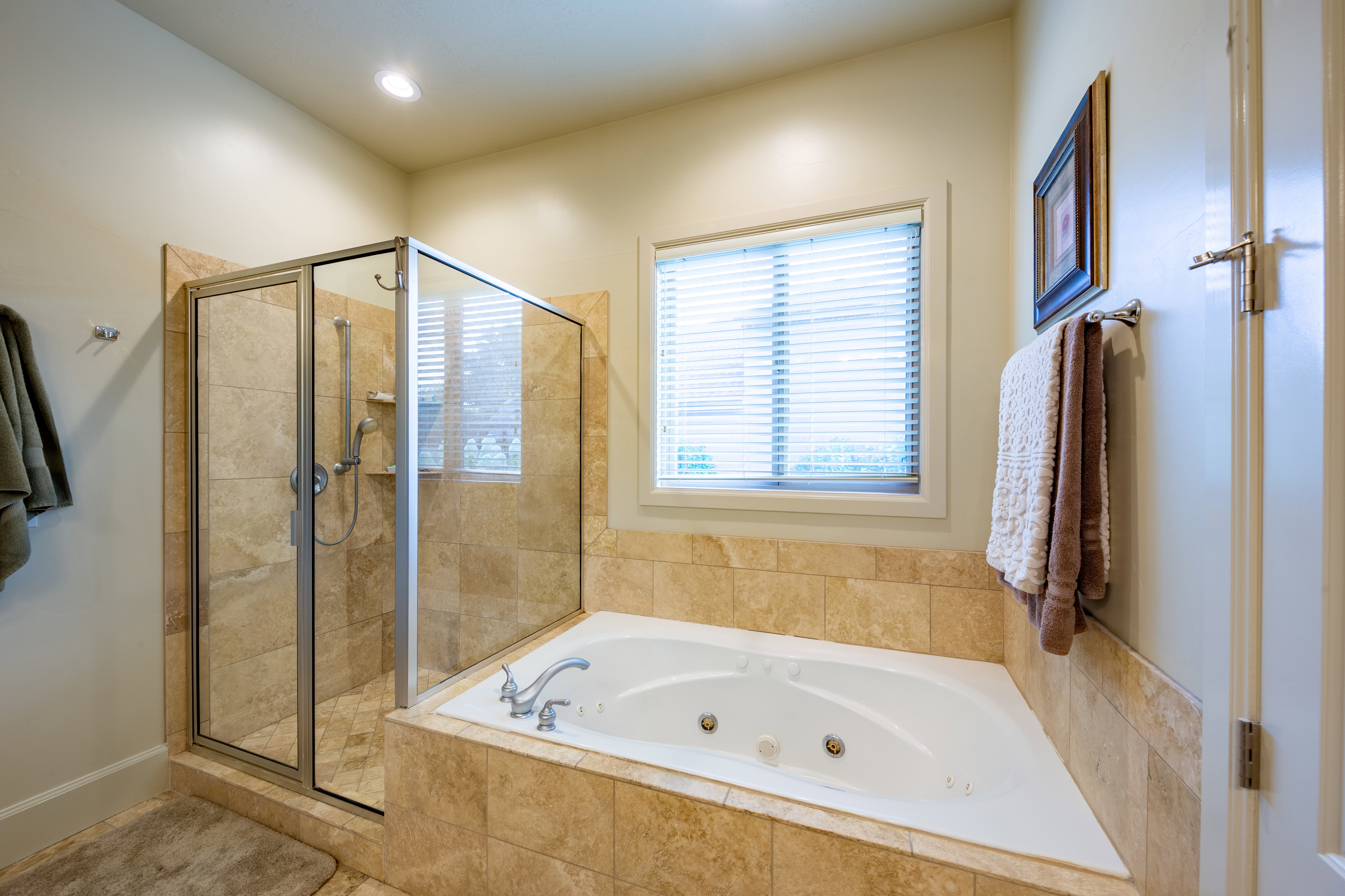 Corner soaking tub with integrated jets, adjacent to a glass-enclosed shower with tile surround