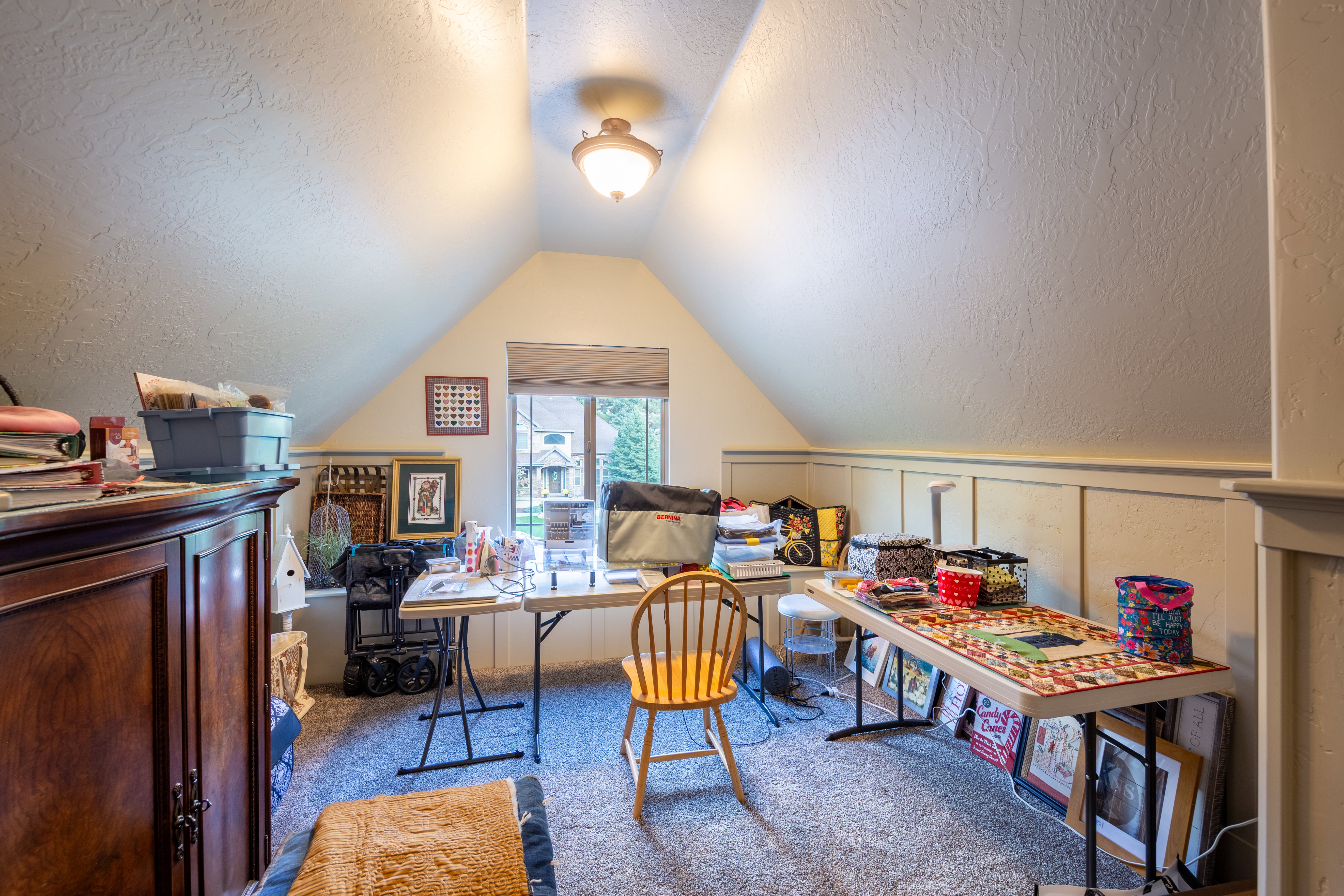 Attic space featuring sloped ceilings, a recessed window, and wall-mounted lighting