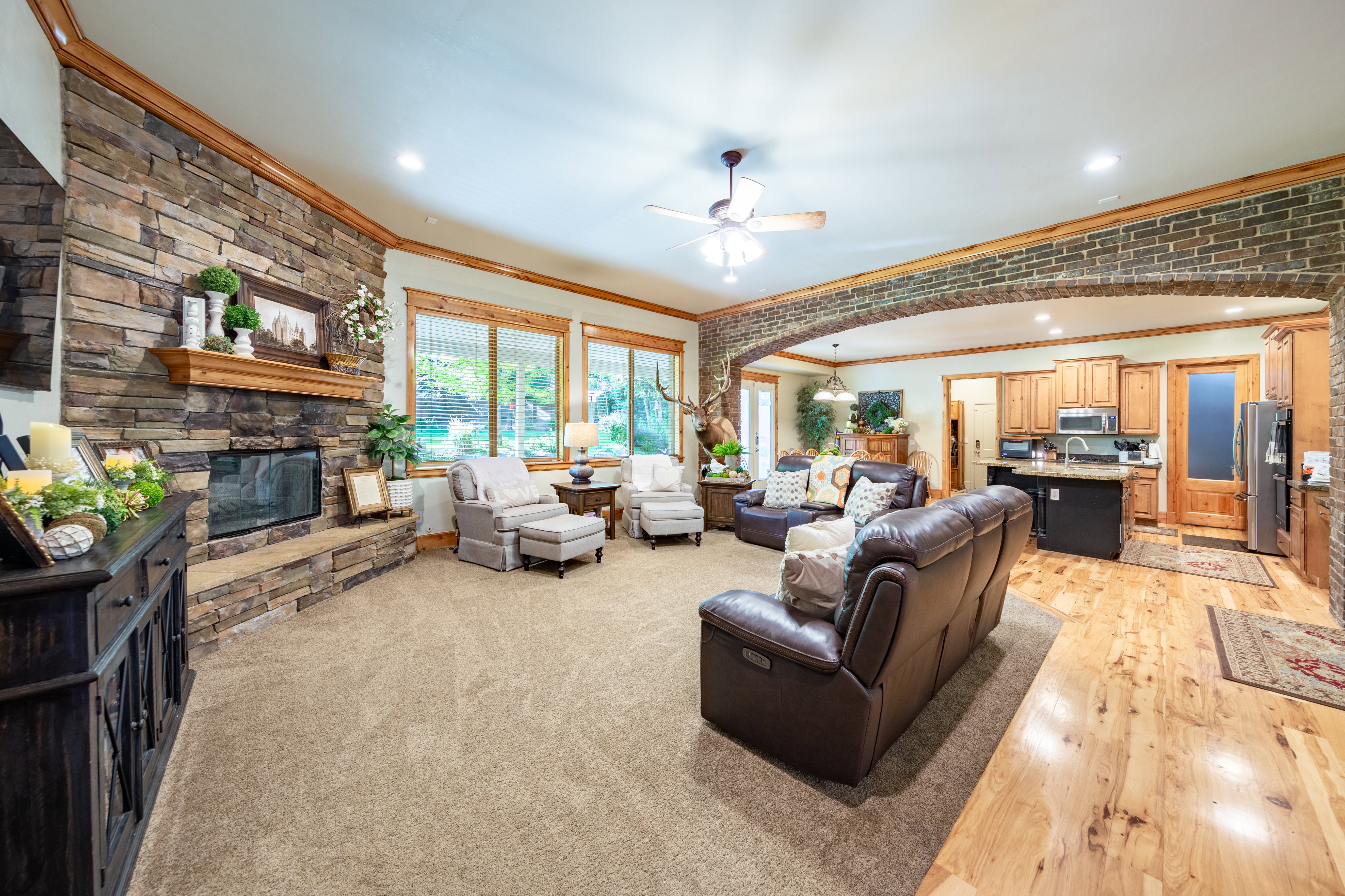 Spacious carpeted living area featuring a floor-to-ceiling stone fireplace with a wood mantle