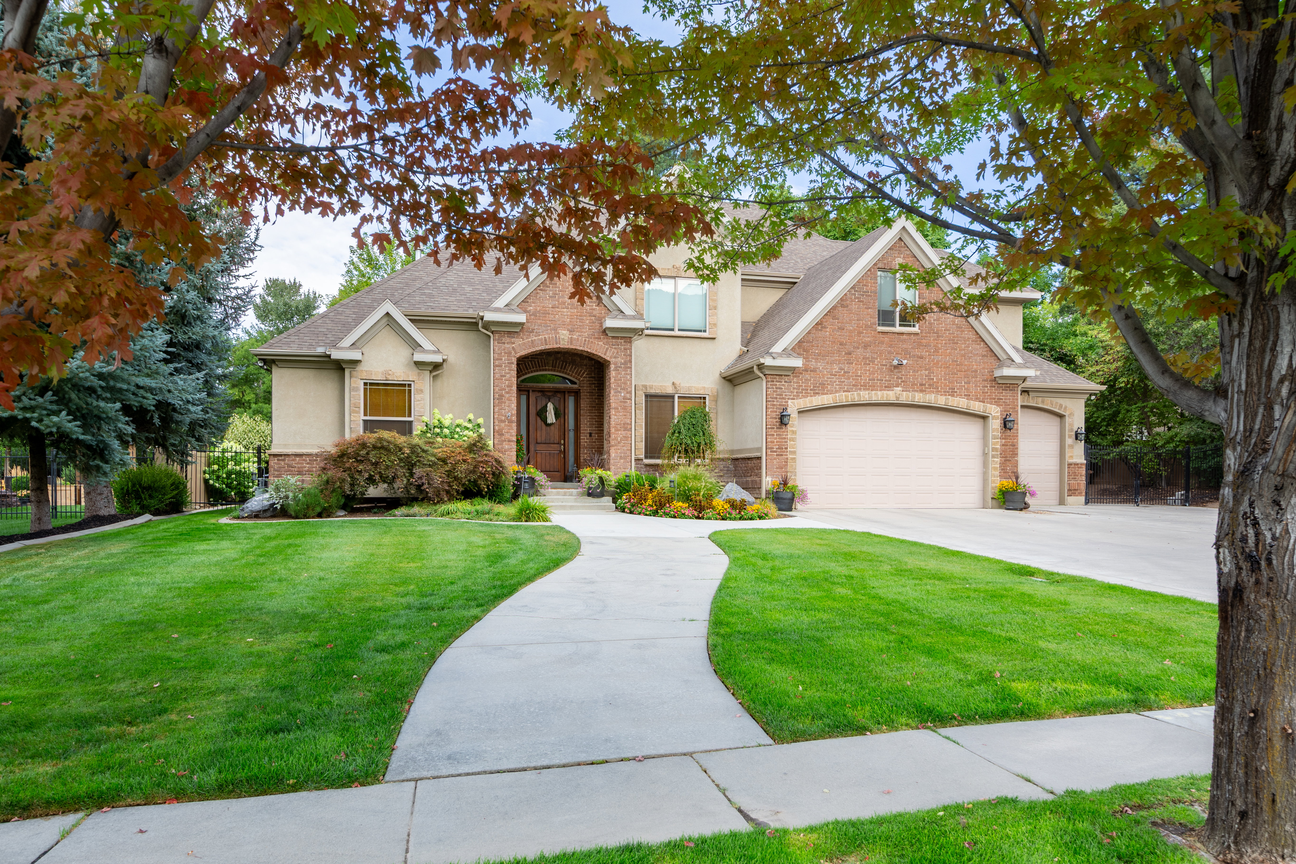 Stately brick and stucco facade featuring an arched entry, a multi-car garage, and a curved concrete driveway
