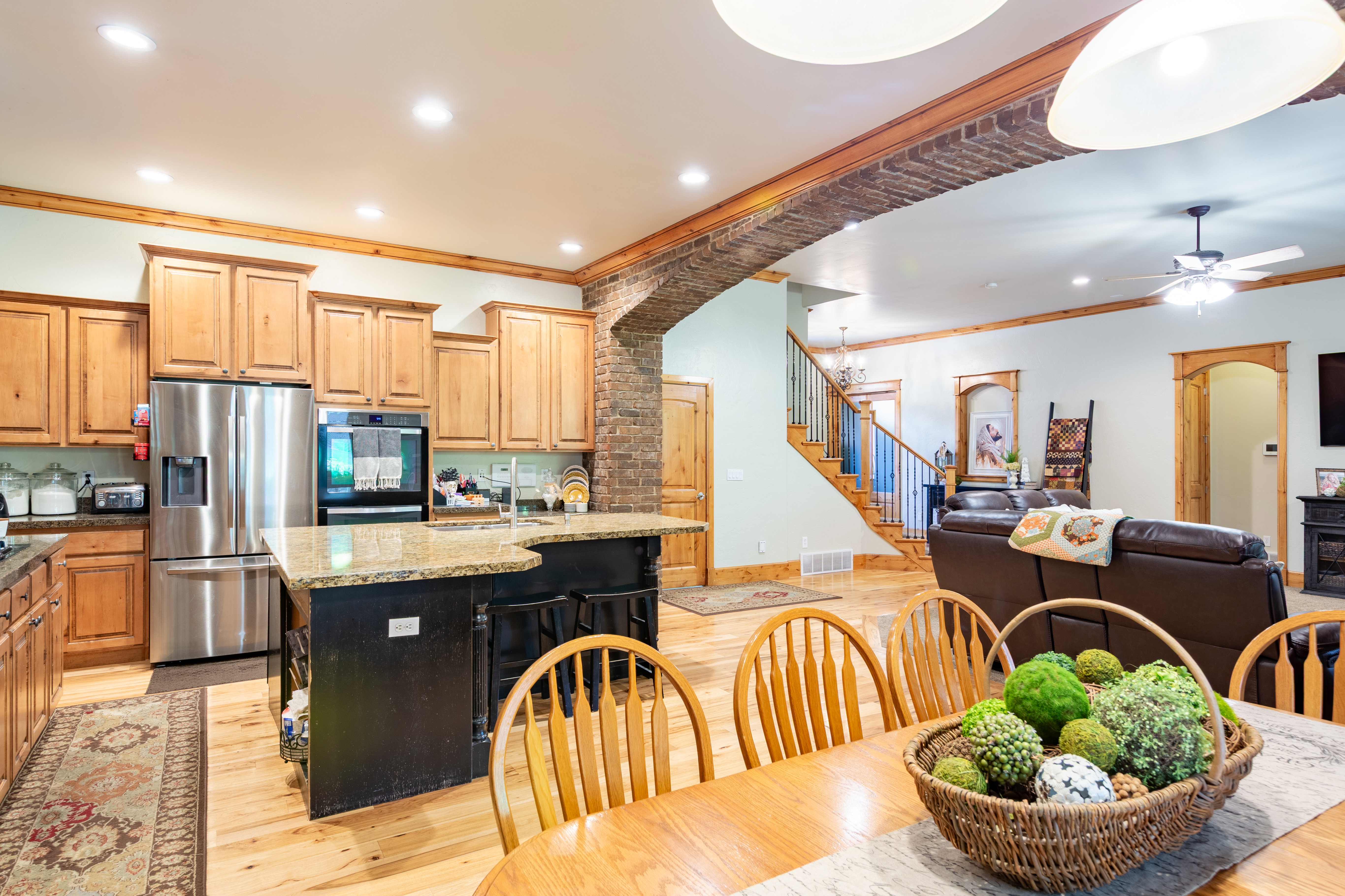 Open-concept living area featuring a kitchen with light wood cabinetry, stainless steel appliances, and granite countertops