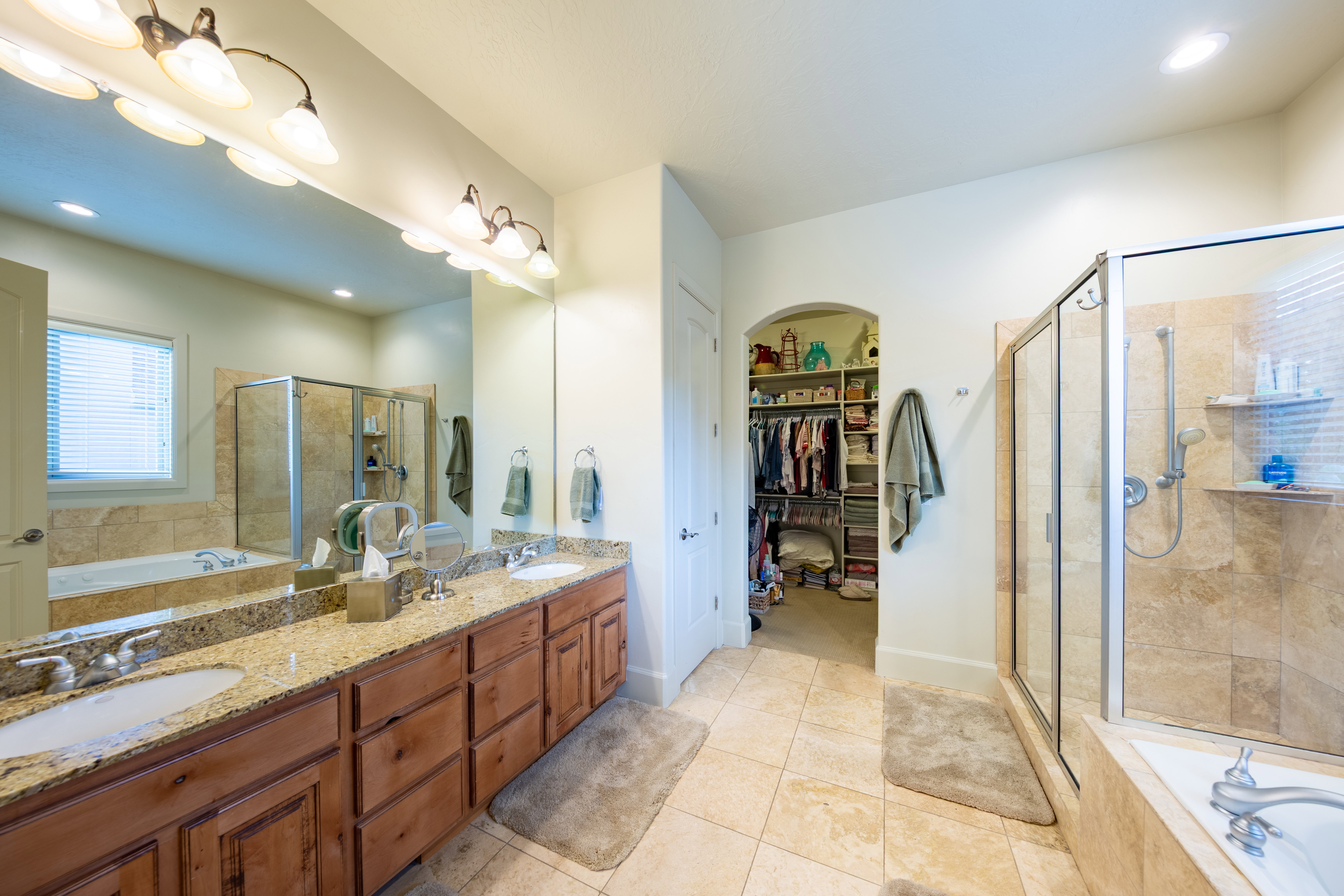 Bathroom featuring a dual vanity with a speckled countertop, integrated sinks, and wood cabinetry