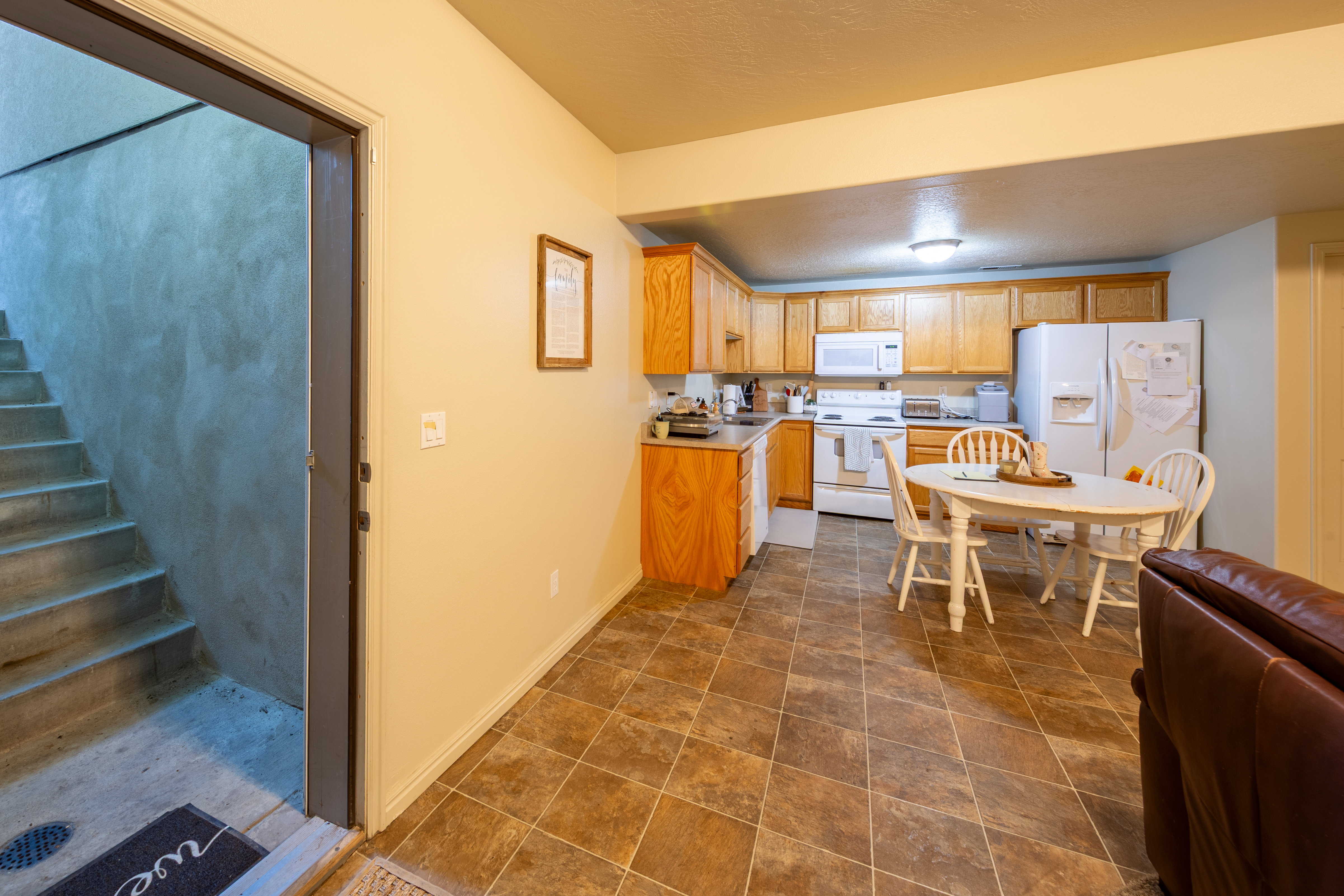 Full kitchen featuring wood-finish cabinetry, white appliances, and a tiled floor