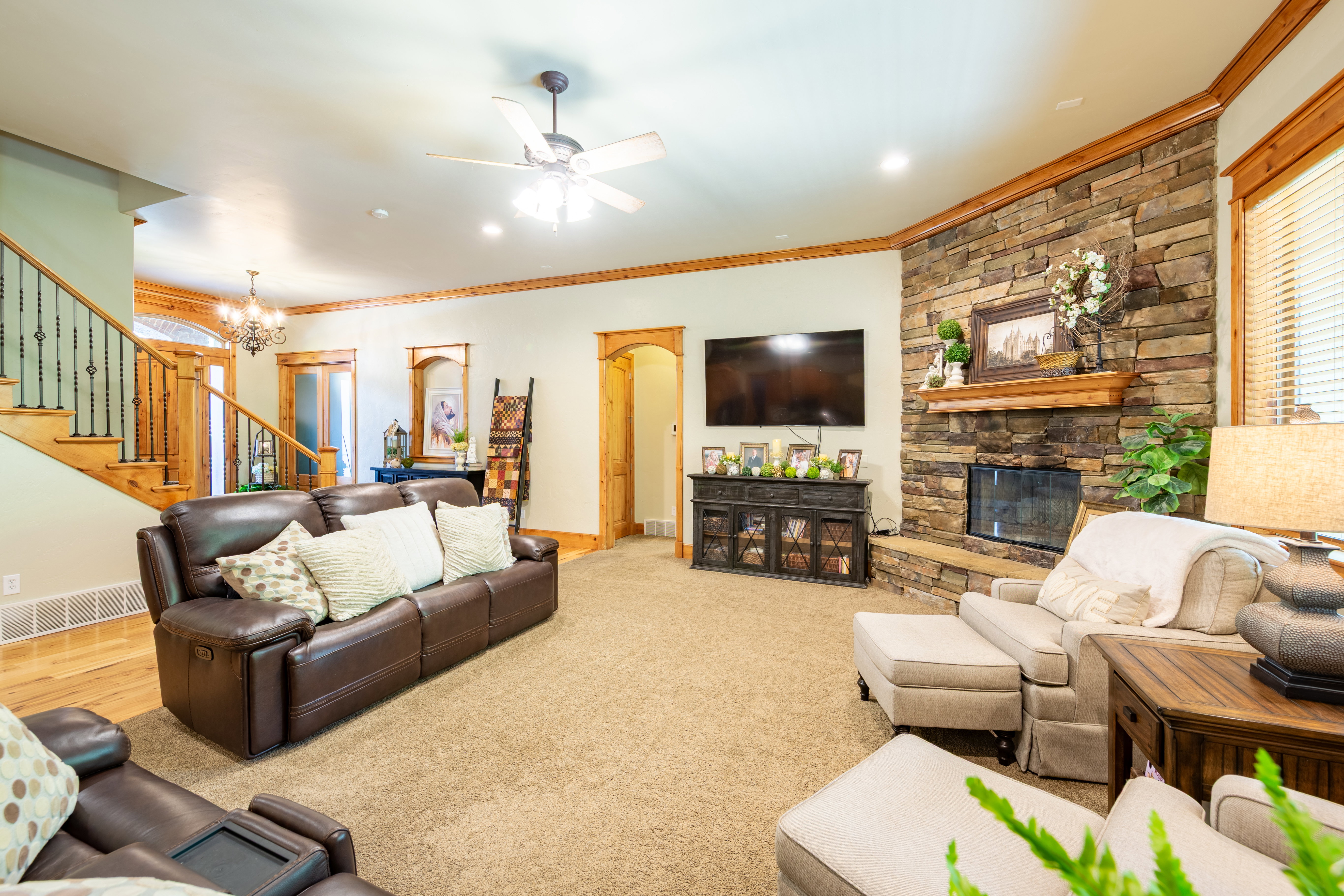 Spacious living area featuring a floor-to-ceiling stone fireplace with a wood mantle, recessed lighting, and a ceiling fan