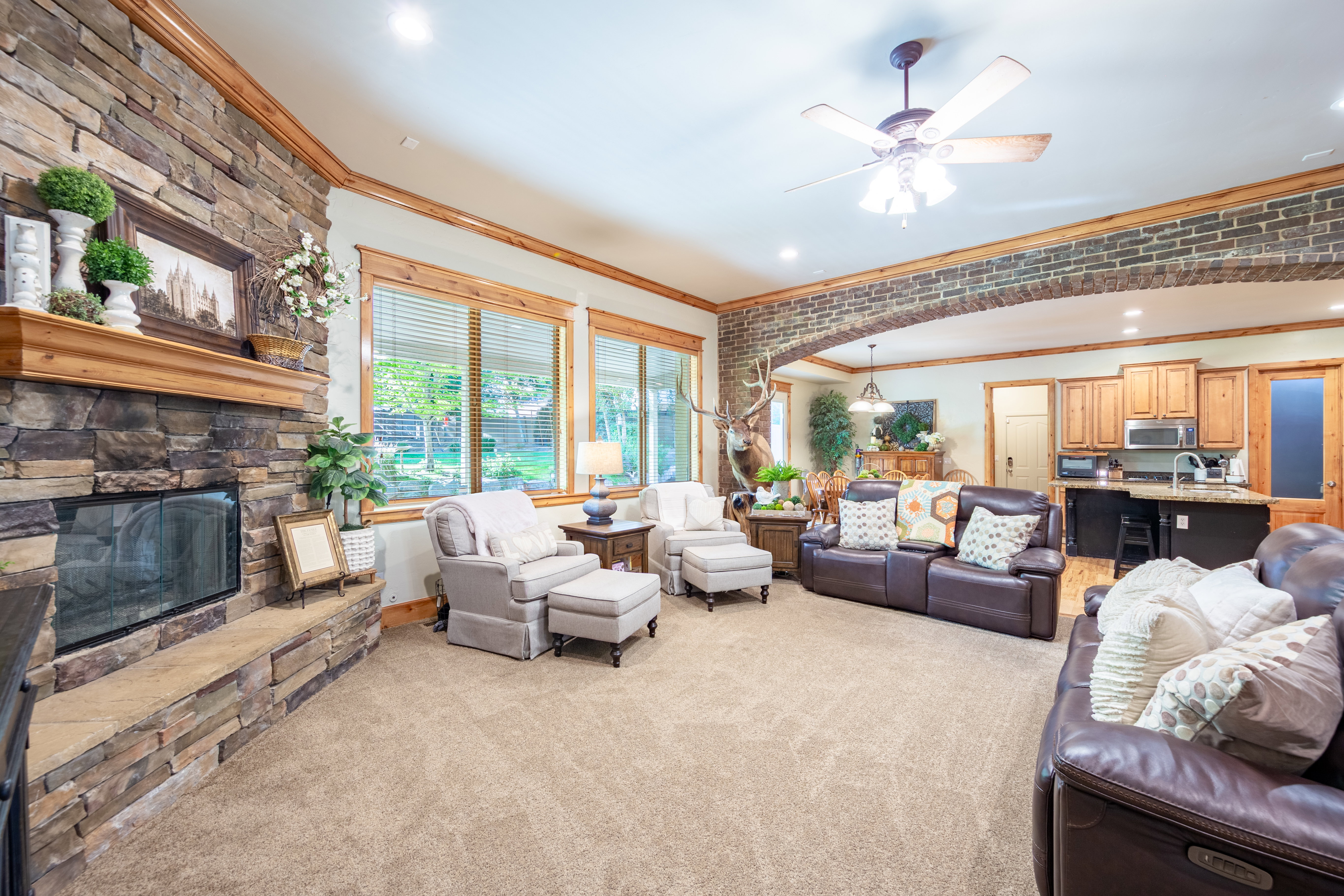 Spacious living area featuring a floor-to-ceiling stone fireplace, large windows, recessed lighting, and a broad arched entryway