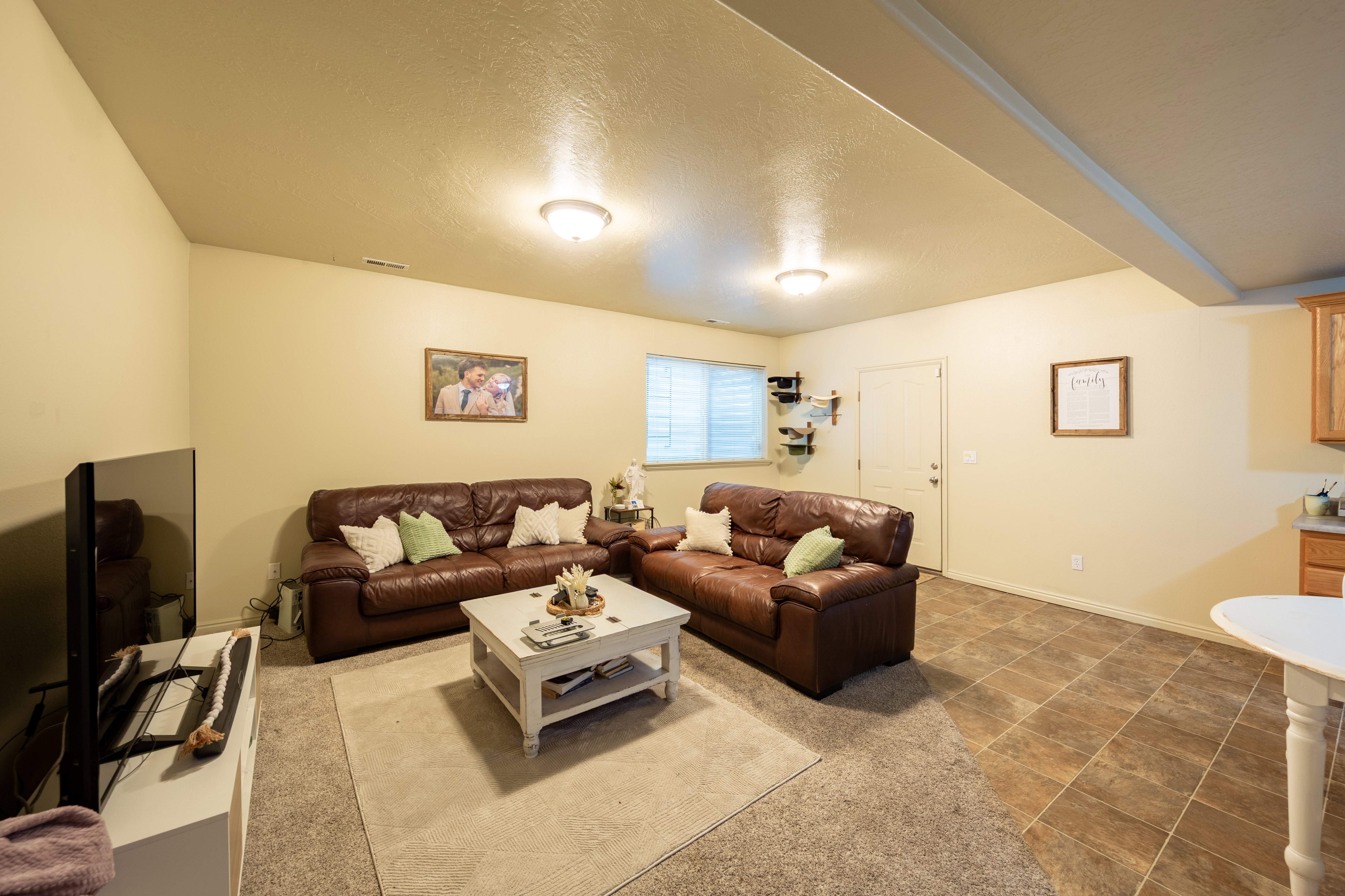 Lower level living area featuring a mix of carpet and tile flooring, recessed lighting, and a window with horizontal blinds