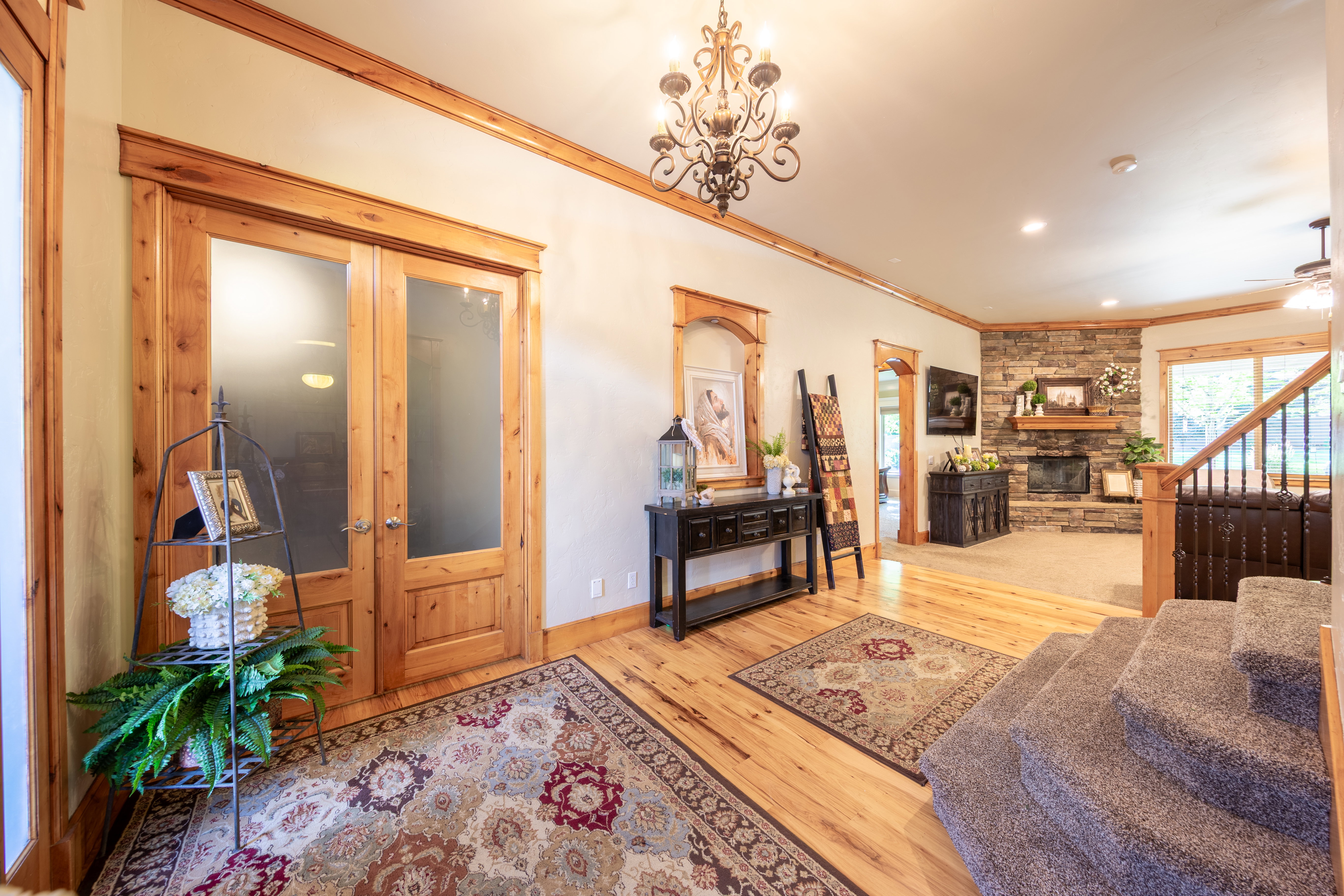 Entryway featuring wood-finish flooring, a wrought iron chandelier, and natural wood trim accents