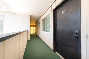 Entryway featuring a black door with modern keyless entry, visible house number, and a green carpeted walkway