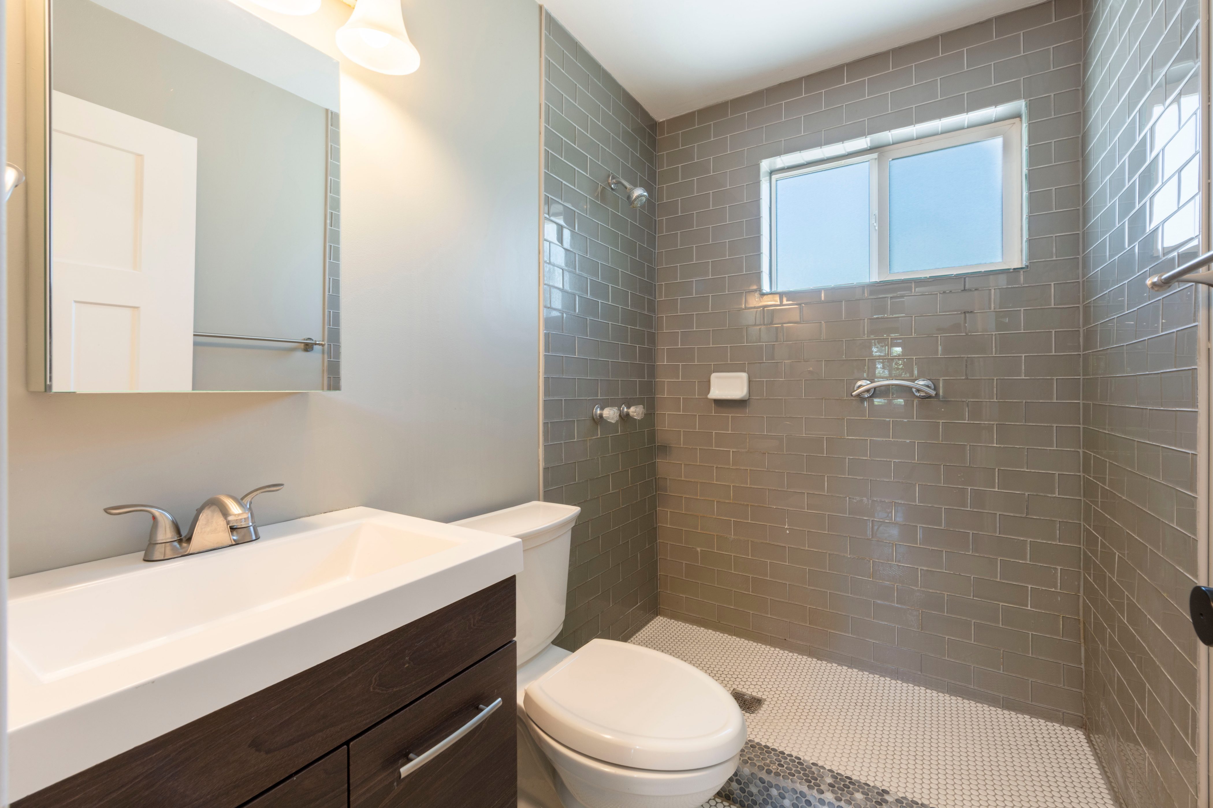 Bathroom featuring a modern vanity with integrated sink, rectangular mirror, and wall-mounted lighting