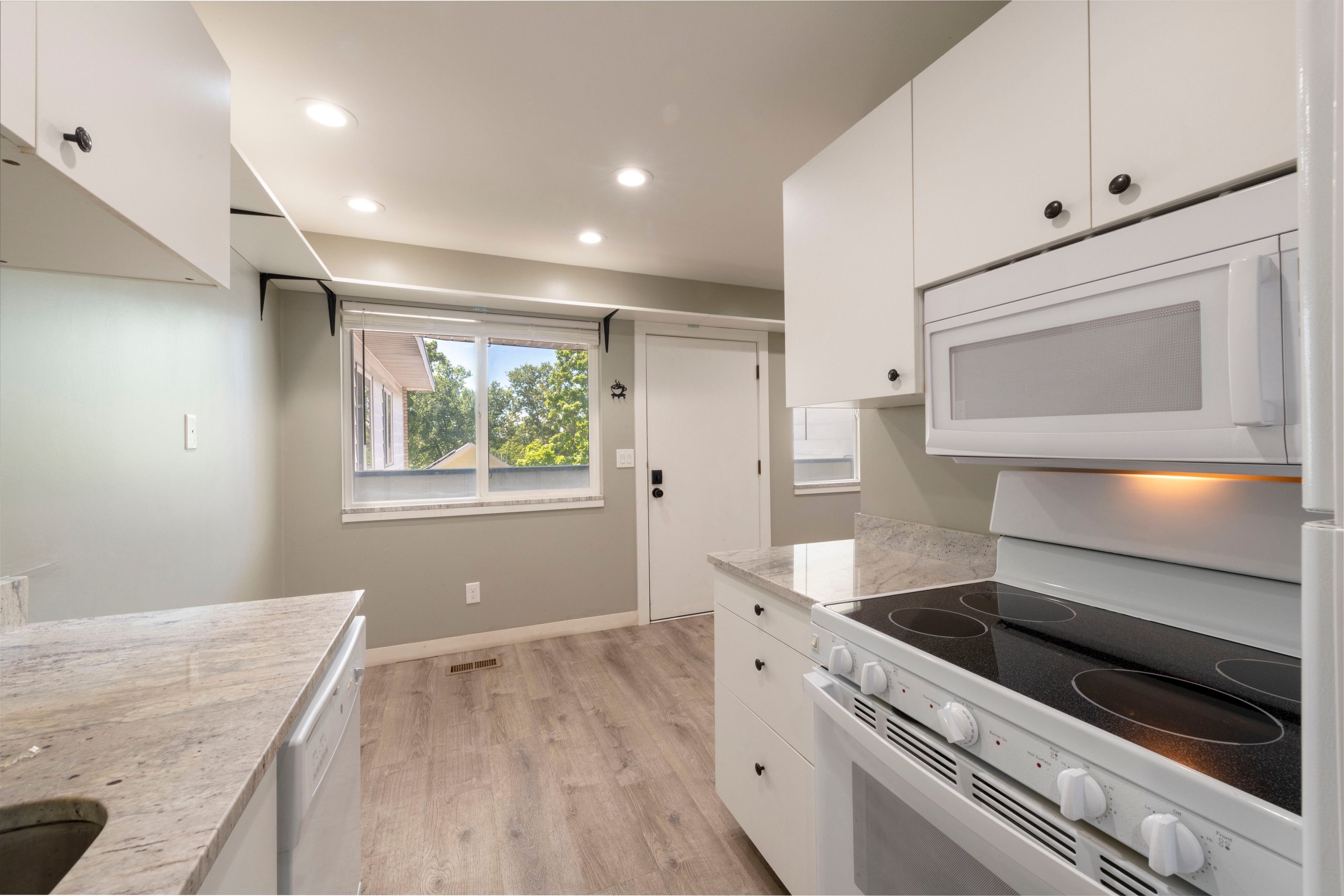 Kitchen featuring white cabinetry with dark hardware, a built-in microwave, and a white electric range with a black cooktop