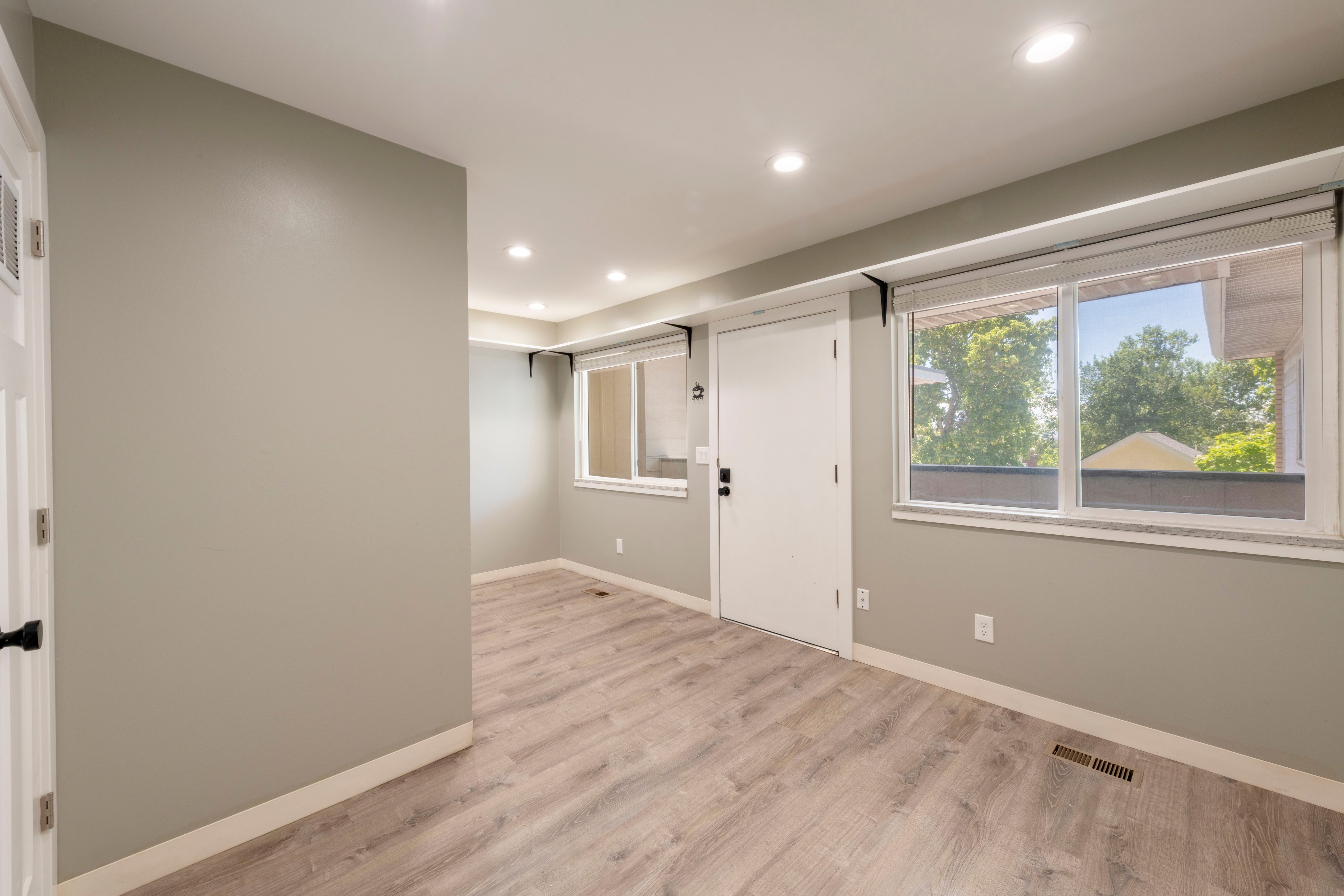 Open room featuring wood-finish flooring, recessed lighting, neutral wall tones, and multiple windows