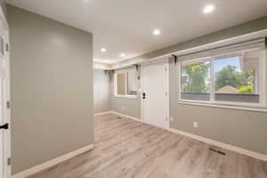 Open room featuring wood-finish flooring, recessed lighting, neutral wall tones, and multiple windows