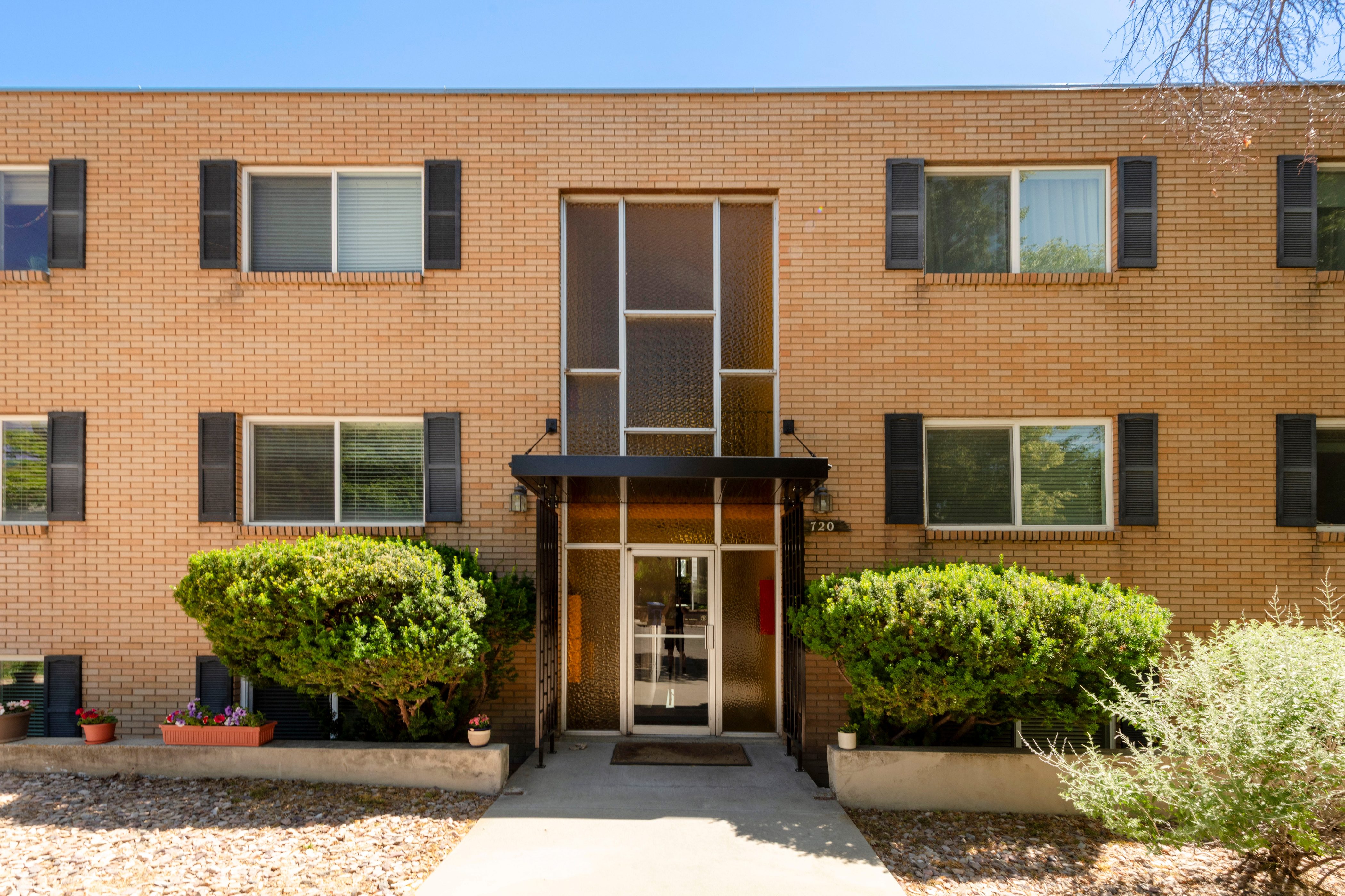 Brick facade building with black louvered shutters and a central glass entry