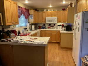 U-shaped kitchen featuring wood cabinetry, wood-finish flooring, a white tile countertop, and a white tile backsplash with red accent tiles