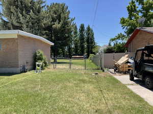 Expansive backyard space featuring a chain-link fence with double gates, mature trees, and a brick exterior building