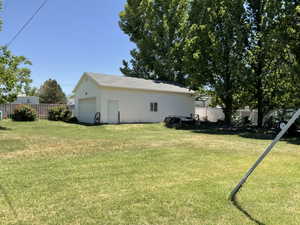 Detached garage with white siding, a single garage door, and a side entry door