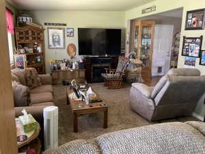 Living area featuring a textured carpet, light green wall paint, and a built-in media console with a fireplace