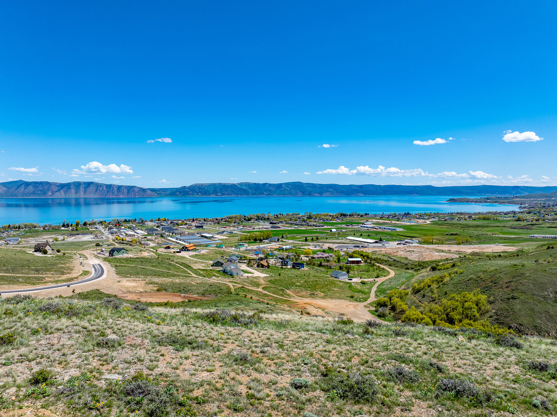 Expansive landscape featuring a large body of water bordered by distant mountains and a residential area
