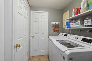 Dedicated laundry room featuring tile flooring, neutral wall color, and white shelving for storage